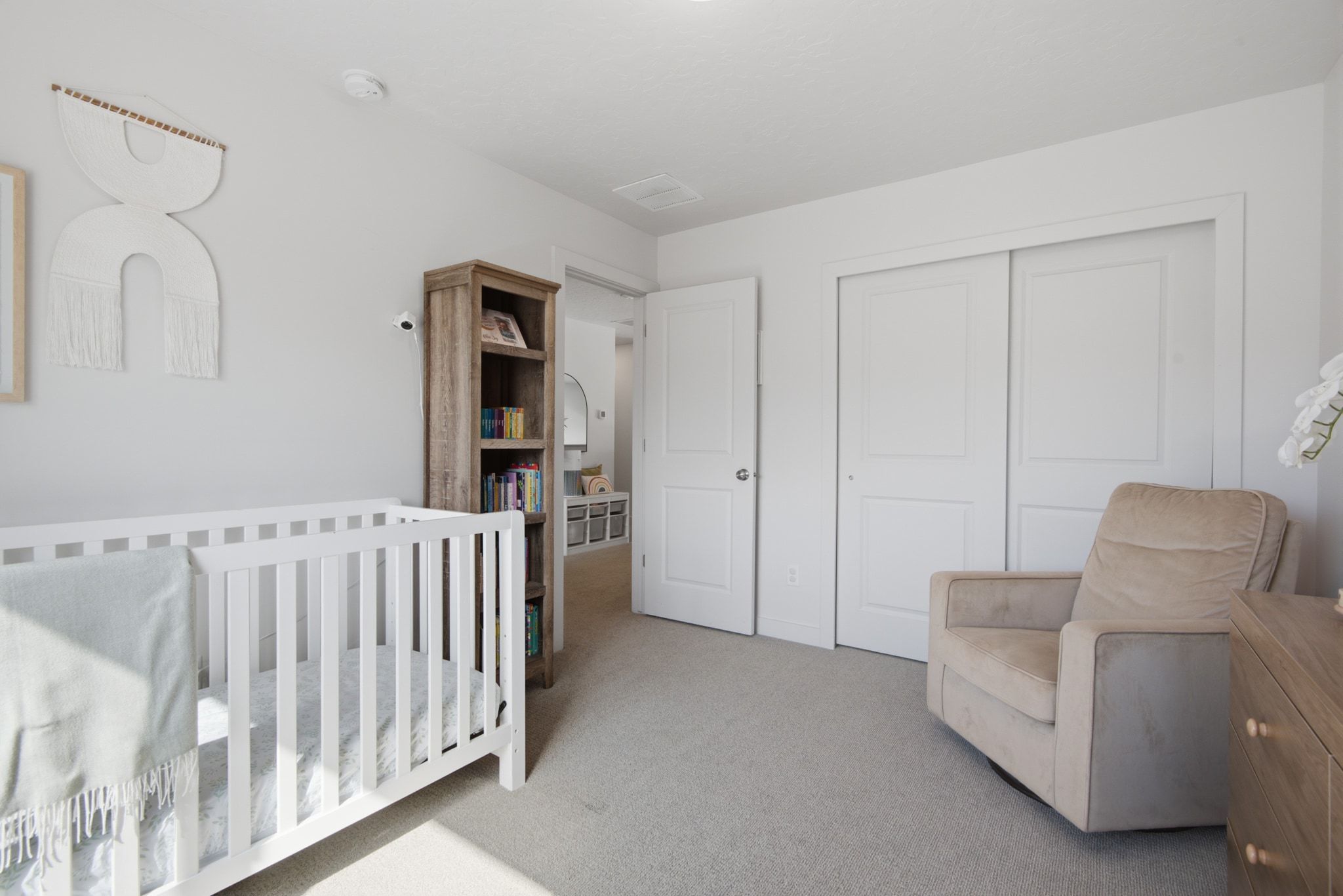 Carpeted room featuring a white crib and a built-in closet with sliding panel doors