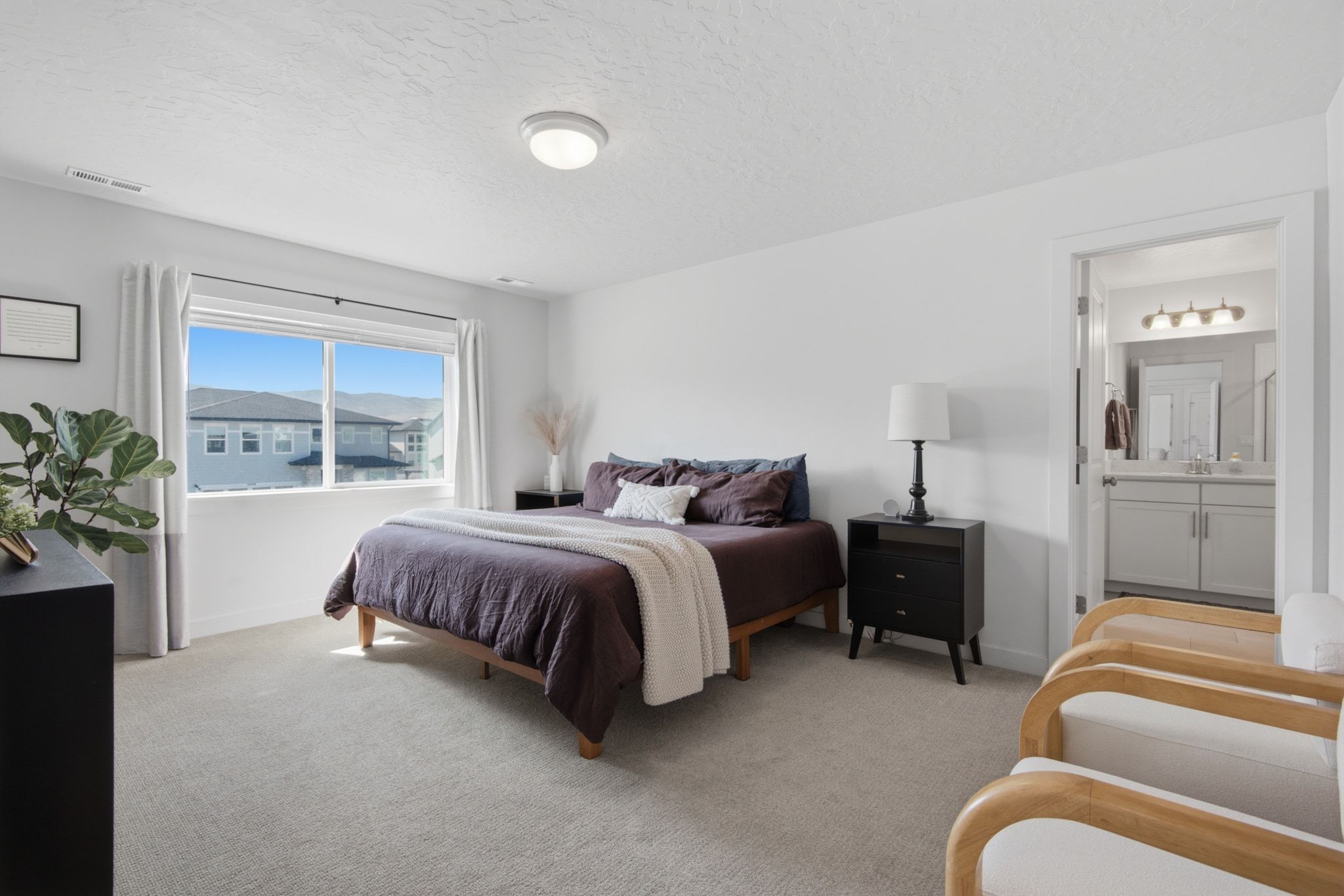 Bedroom featuring light gray carpeting, a large window, white walls, and an overhead flush-mount light fixture
