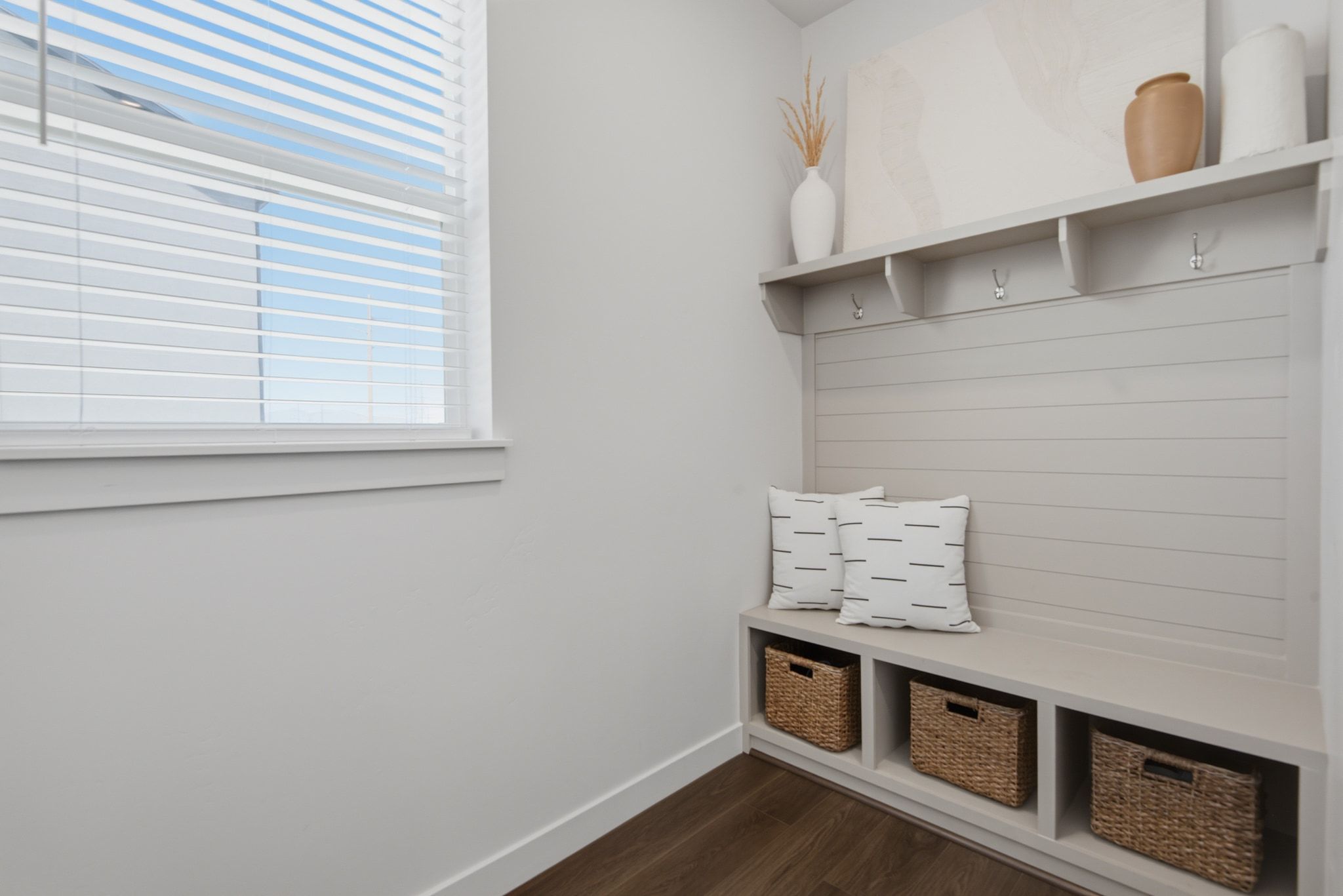 Entryway mudroom bench with built-in storage cubbies, integrated hooks, and an overhead shelf