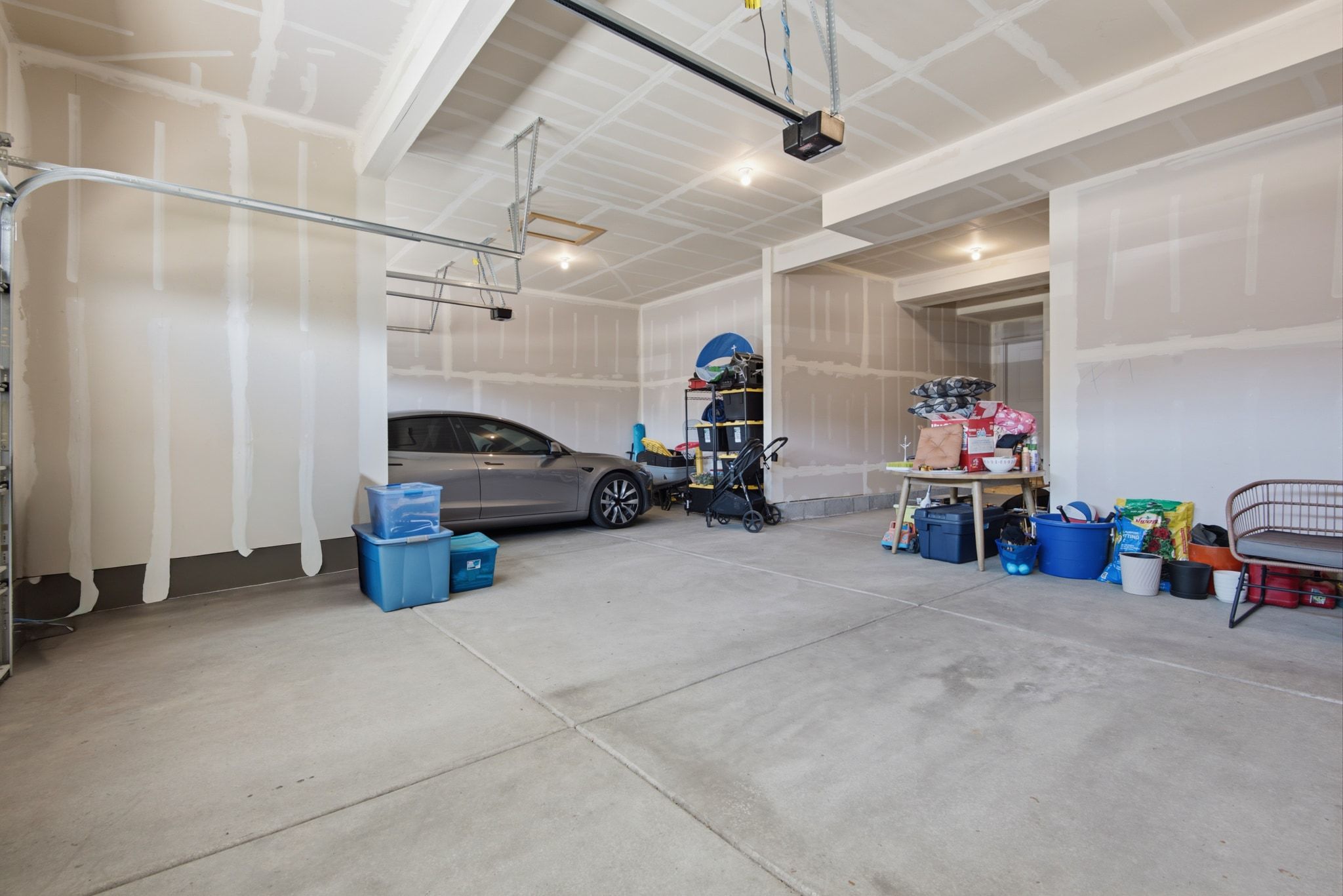Spacious two-car garage featuring a concrete floor, high ceilings, and an automatic garage door opener