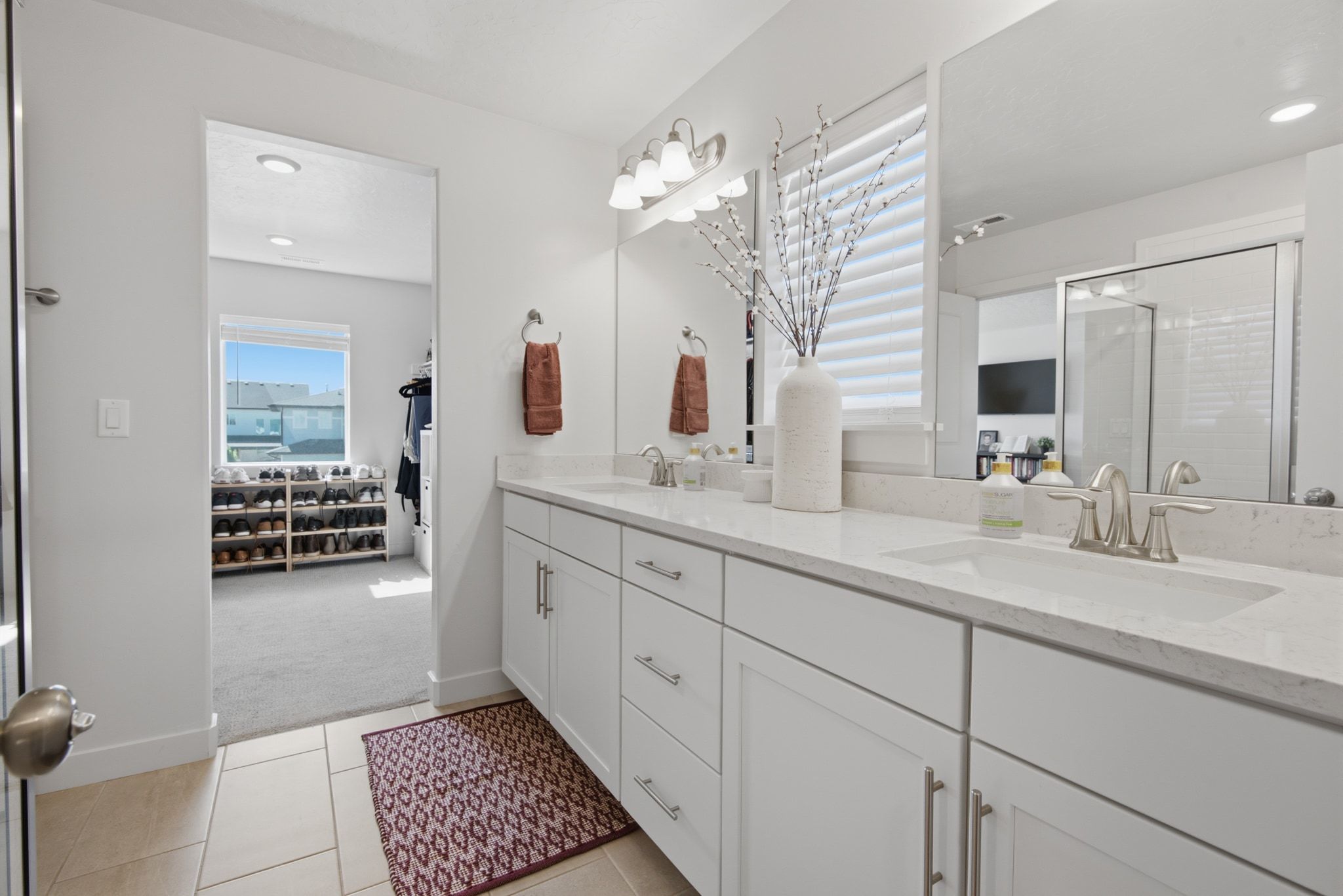 Dual vanity with white cabinetry, light-toned countertops, and brushed nickel fixtures
