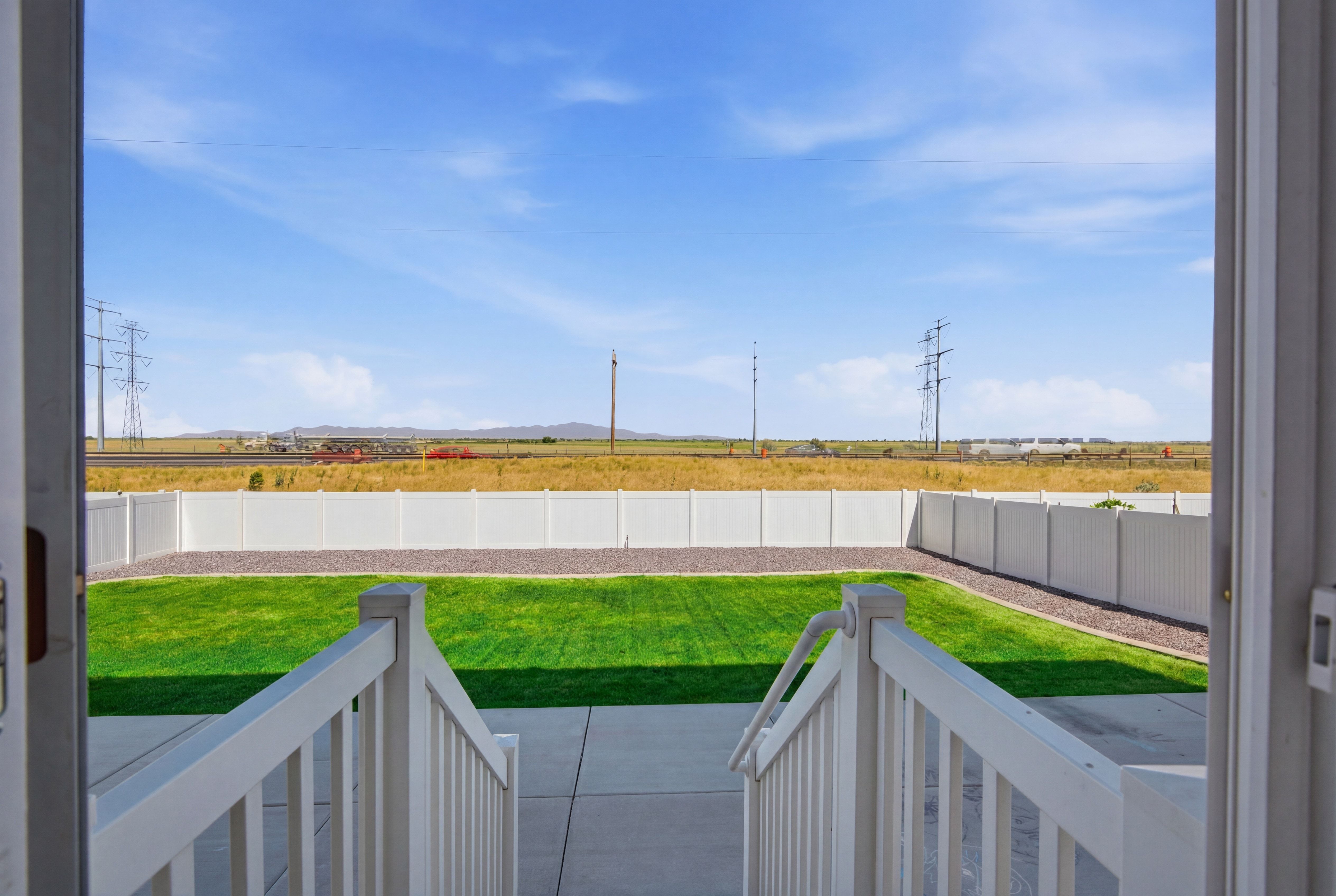 Expansive backyard featuring a vibrant green lawn and a white privacy fence