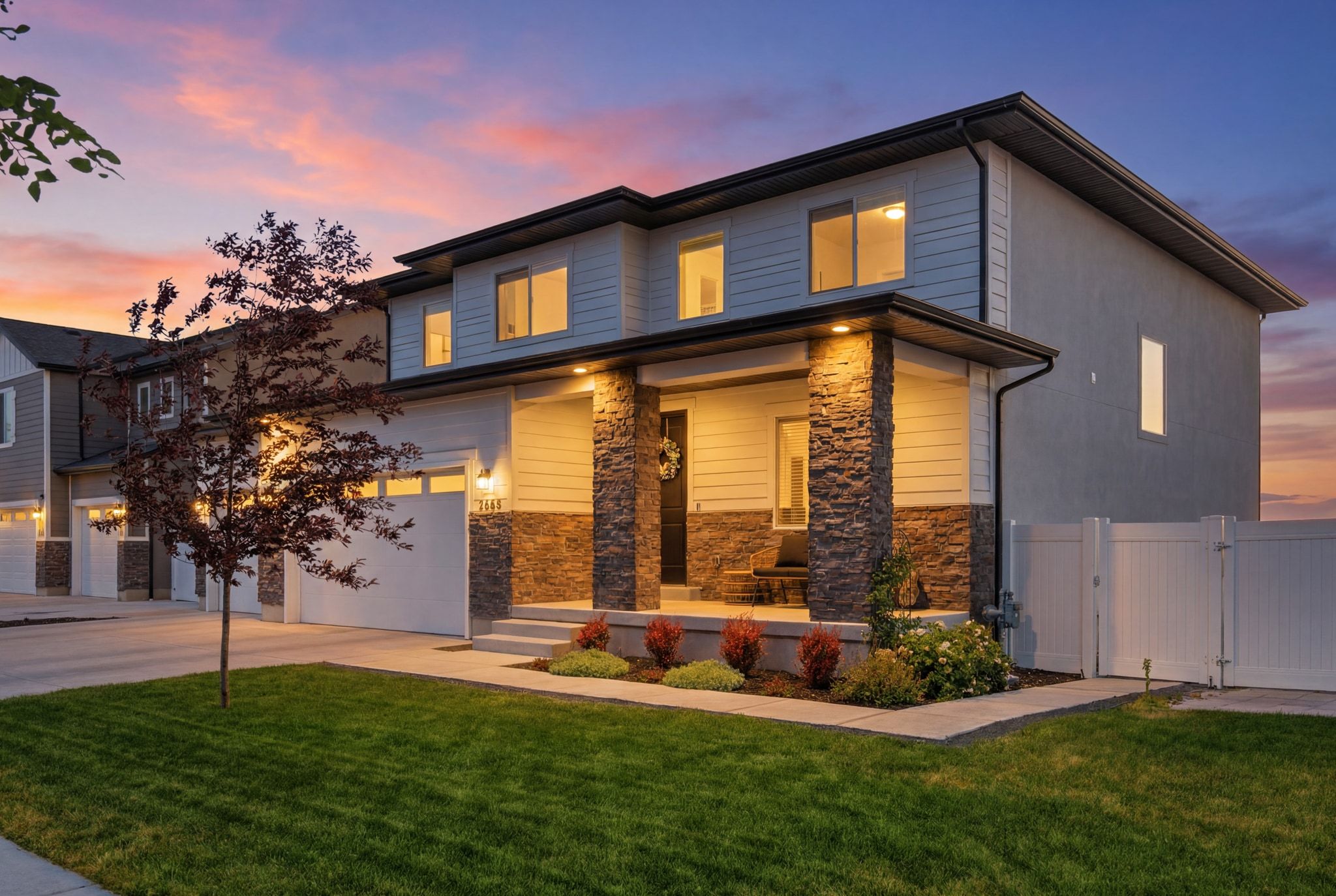 Contemporary residence featuring a covered front porch with stone-clad columns, horizontal siding, and a three-car garage