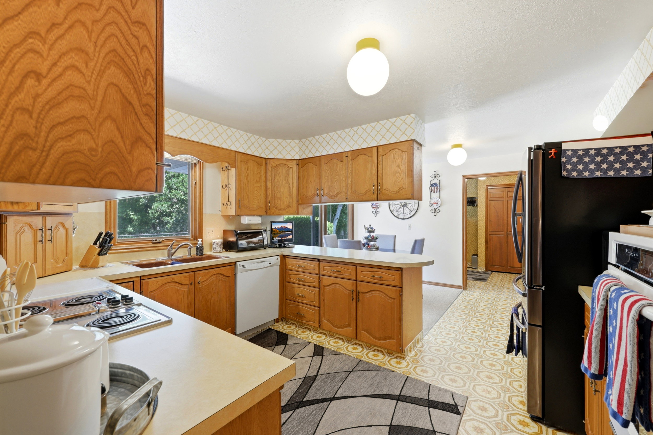 Kitchen featuring wood cabinetry, light-toned countertops, and a double basin sink beneath a window