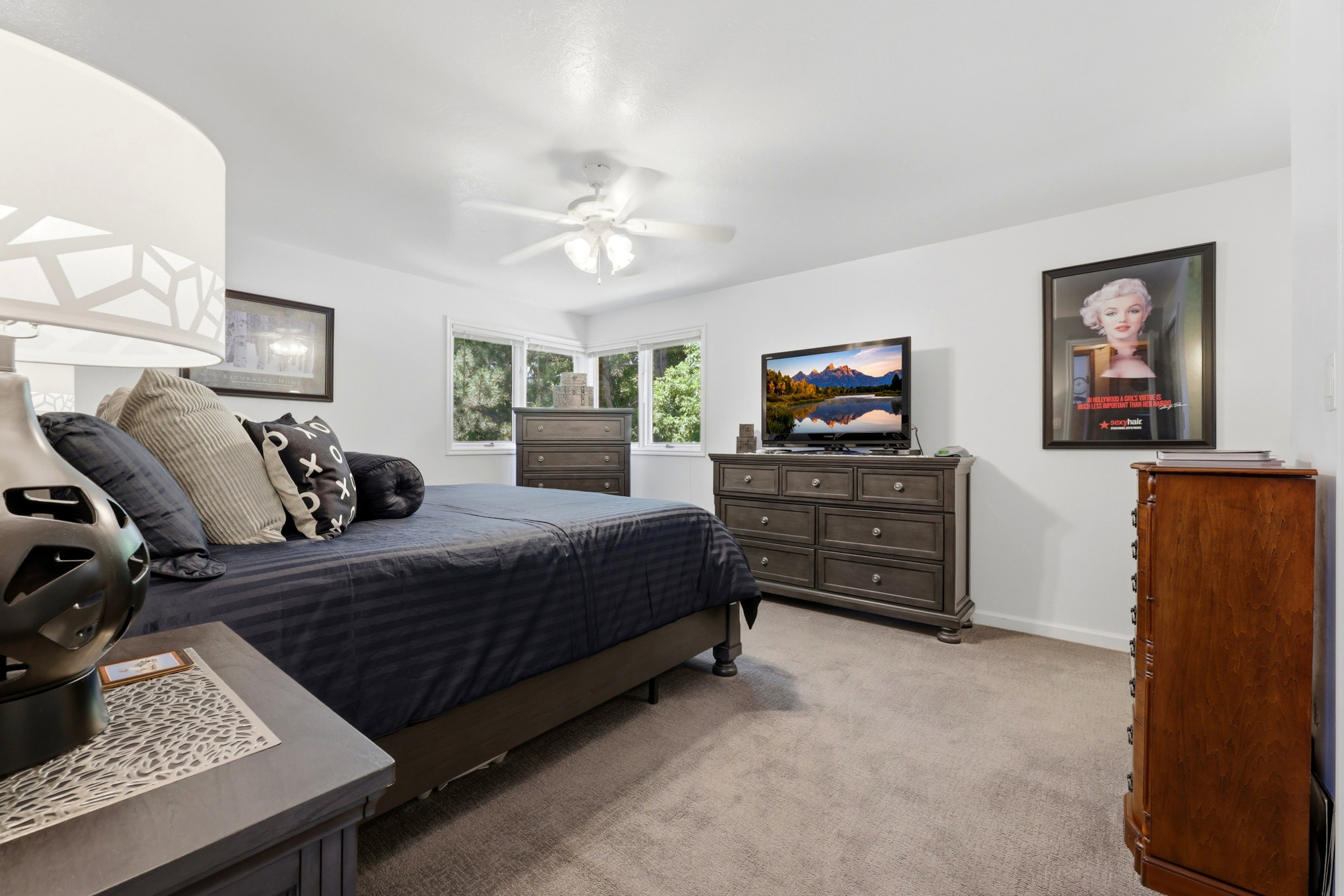 Bedroom featuring expansive bay windows, neutral carpeting, a ceiling fan, and ample wall space