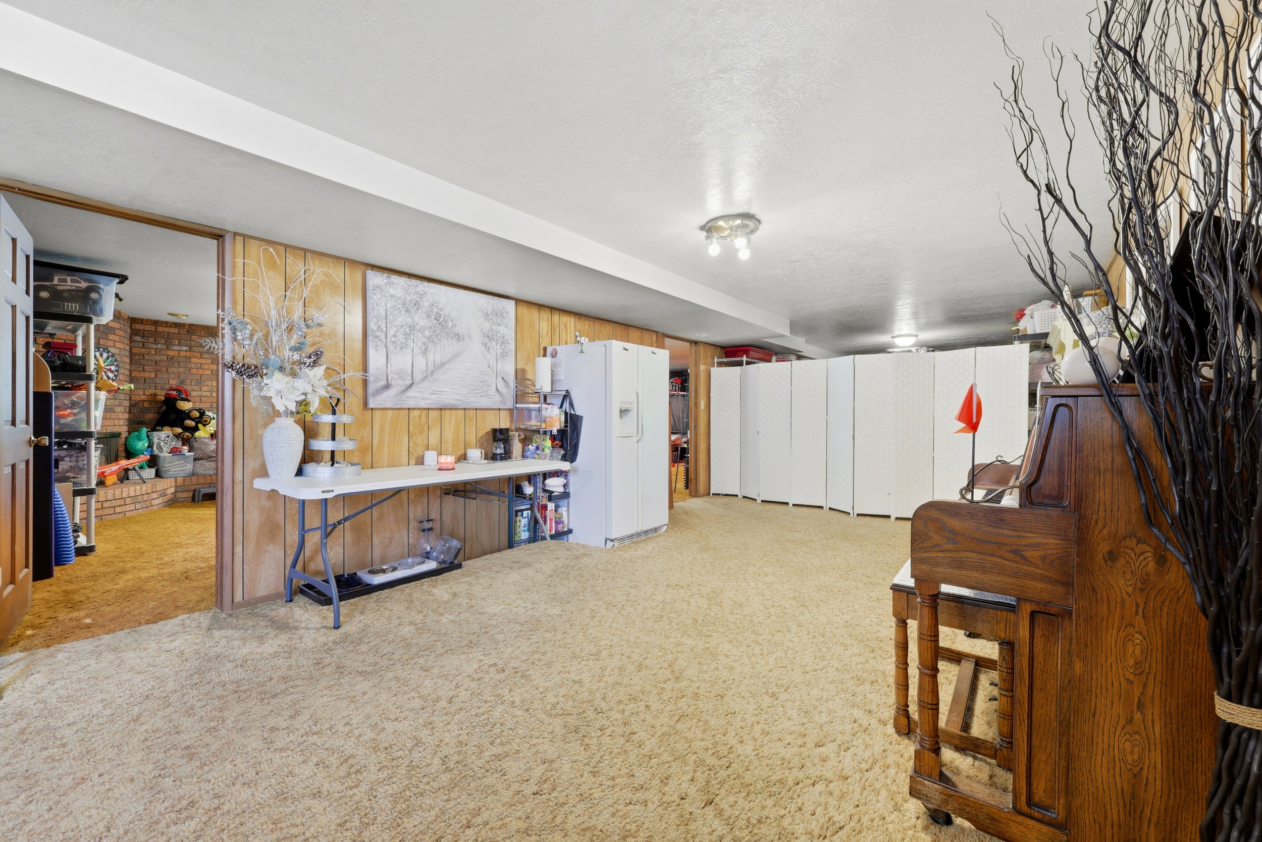 Spacious room featuring wood-panel walls, neutral carpet, recessed lighting, and a white ceiling