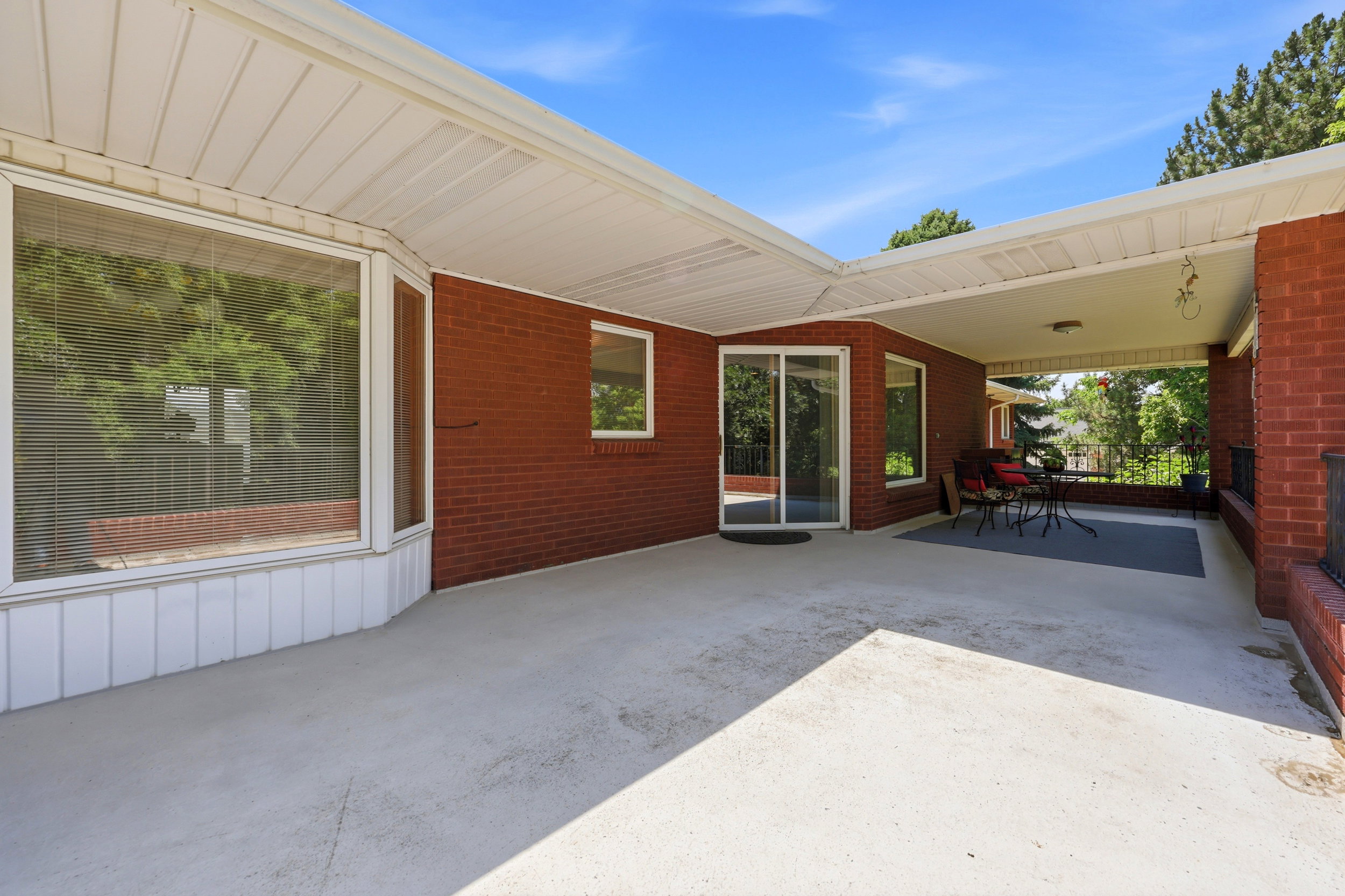 Expansive covered patio featuring a full brick exterior, a large bay window, and a sliding glass door entry