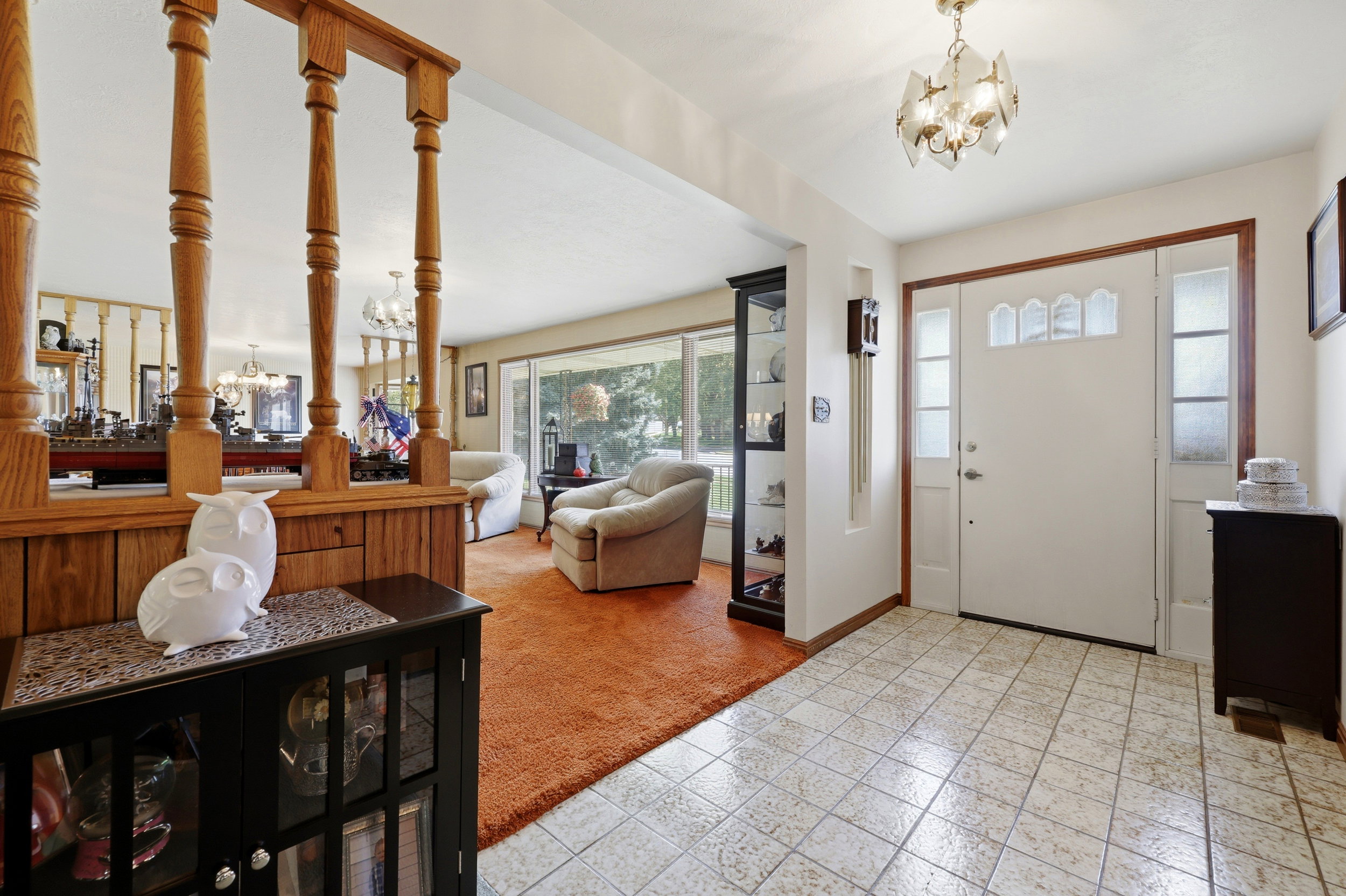 Entryway featuring neutral-toned tile flooring, a white paneled door with decorative glass inserts, and two frosted glass sidelights