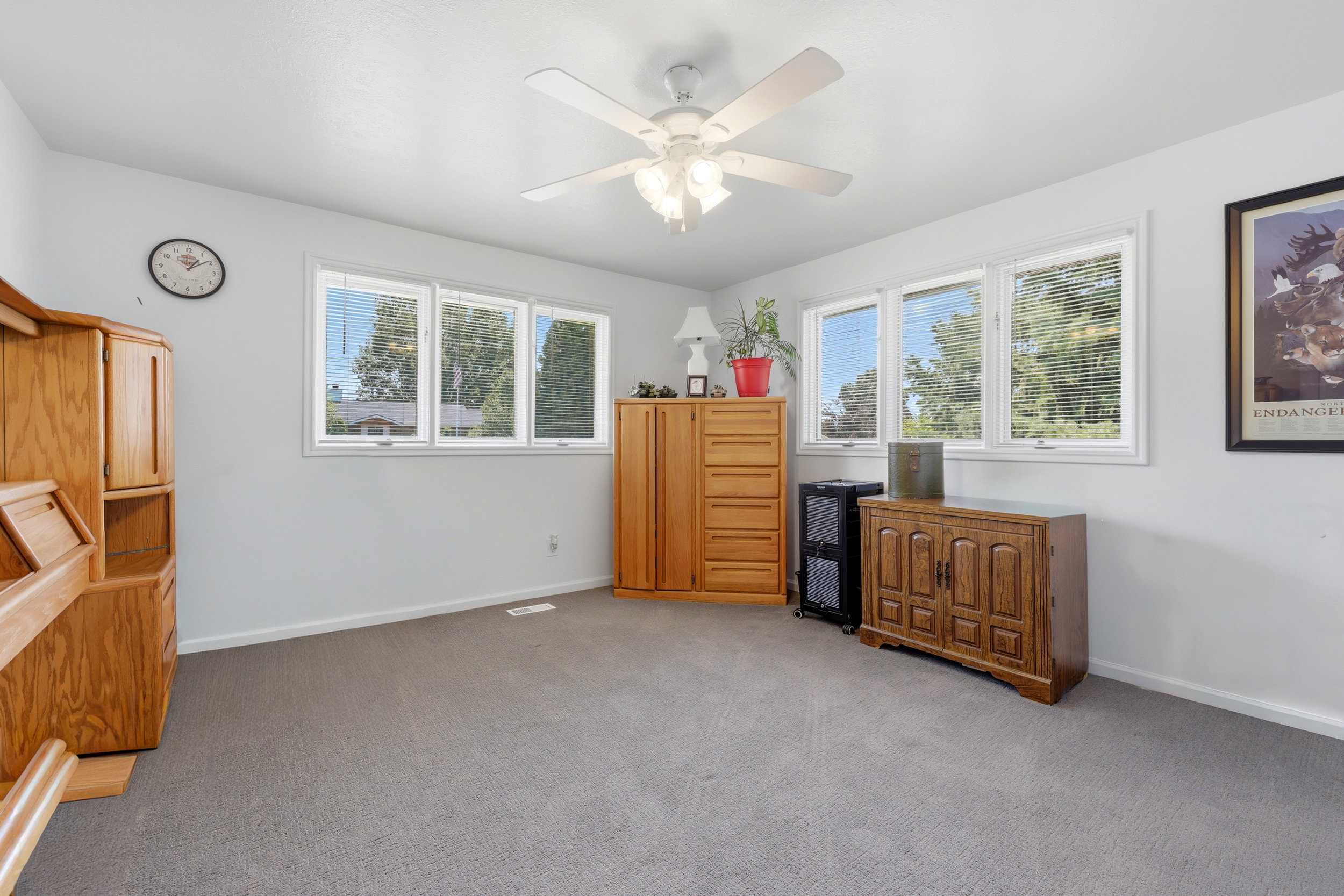 Room featuring light gray carpeting, neutral wall paint, white trim, and a white ceiling fan with integrated lighting