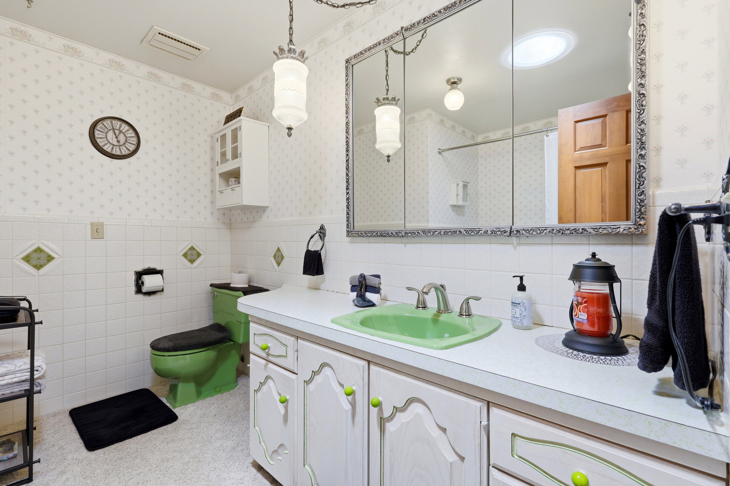 Bathroom vanity featuring a green basin, dual-handle faucet, and white countertop