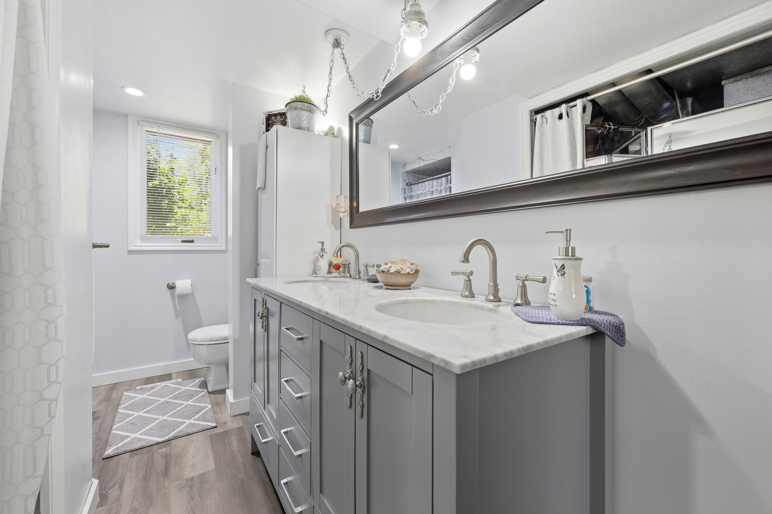 Double vanity featuring a light gray base cabinet, white countertop, and dual undermount sinks with brushed nickel faucets