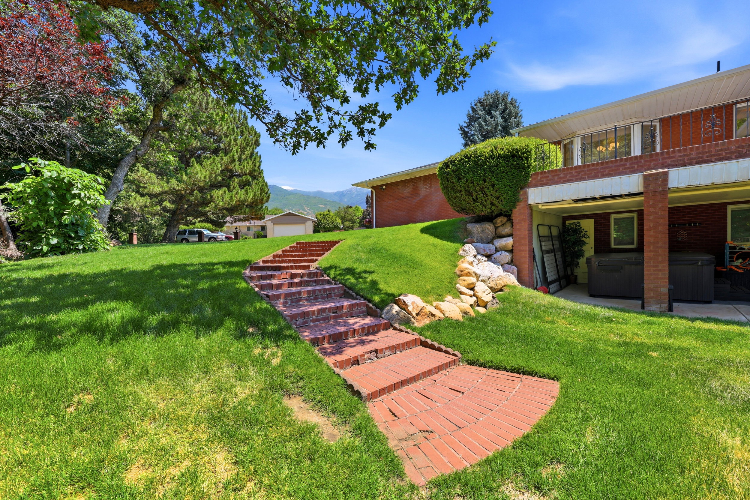 Tiered landscaping with a winding brick staircase and mature trees