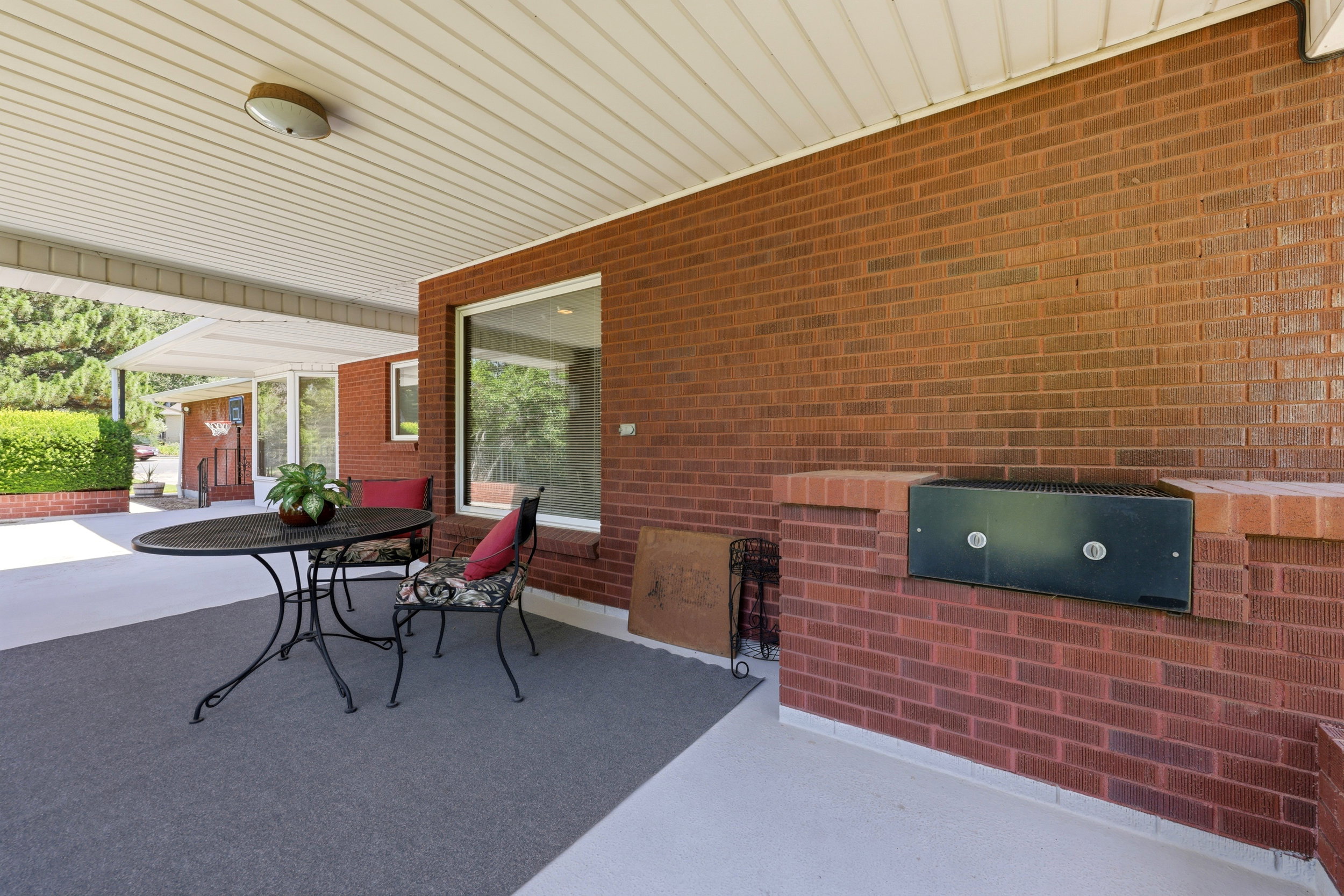 Covered patio featuring a slatted white ceiling, a built-in brick barbecue, an integrated outdoor grill, and expansive brick exterior walls