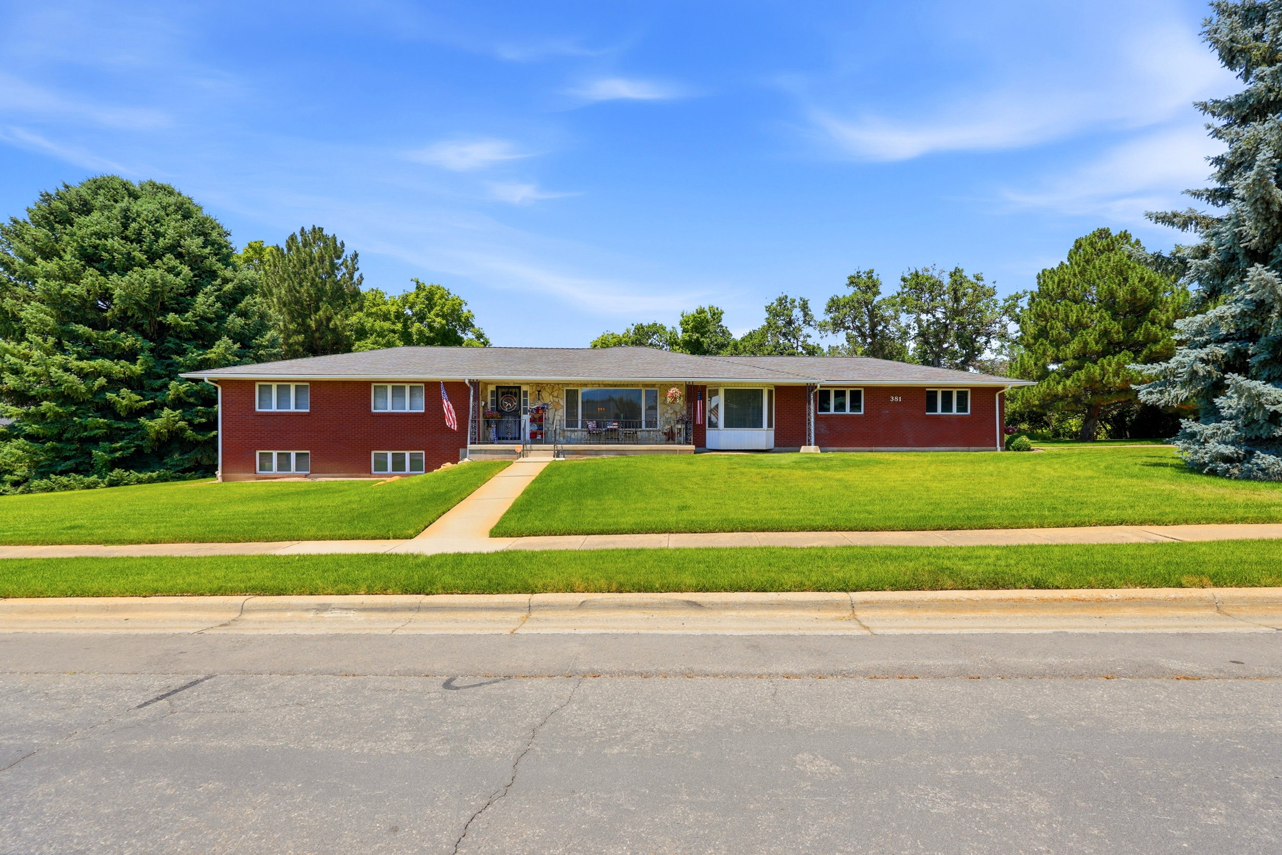 Split-level residence featuring a red brick exterior, a paved walkway, and a spacious front lawn