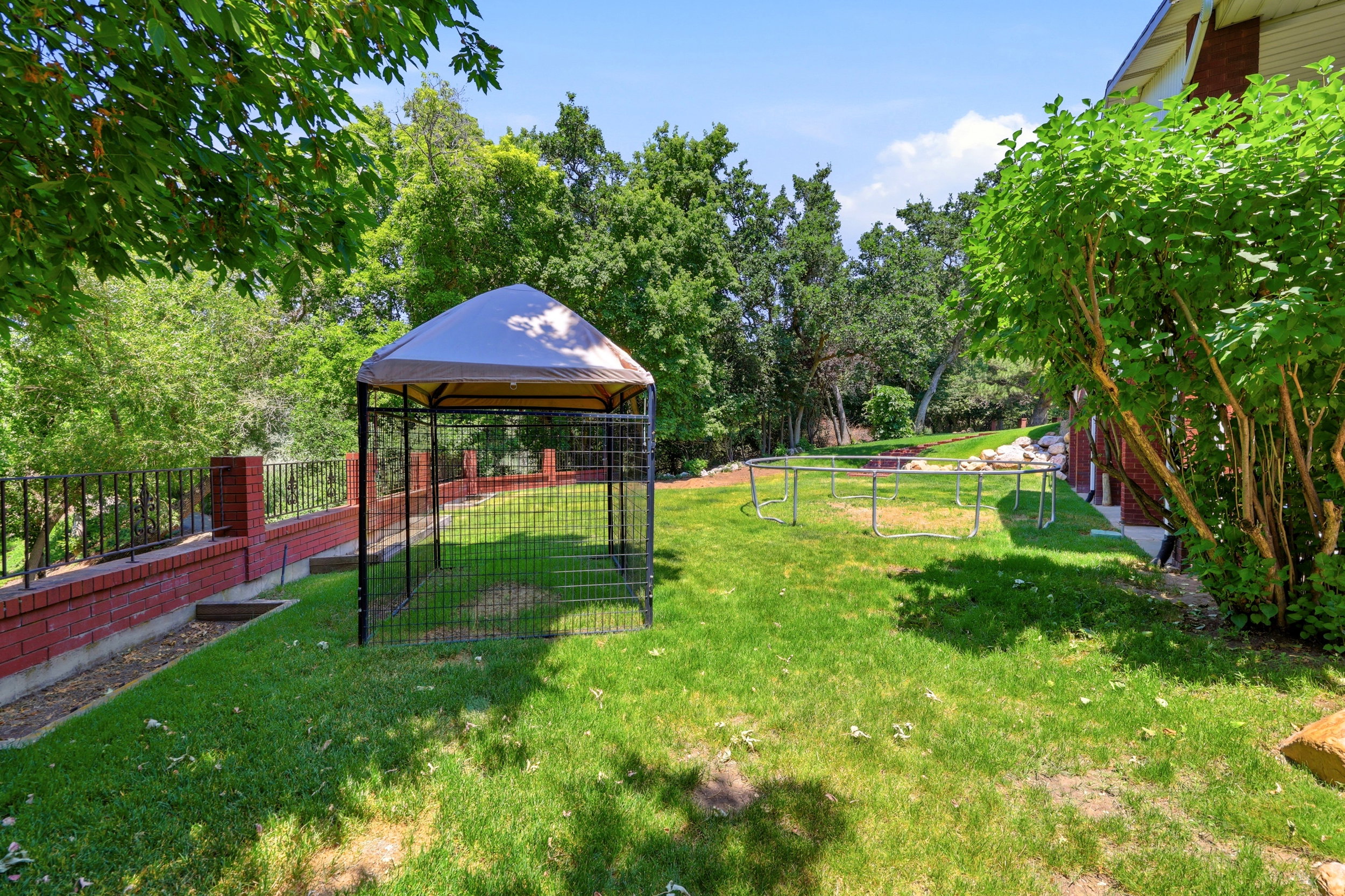 Expansive green lawn with mature trees and perimeter fencing