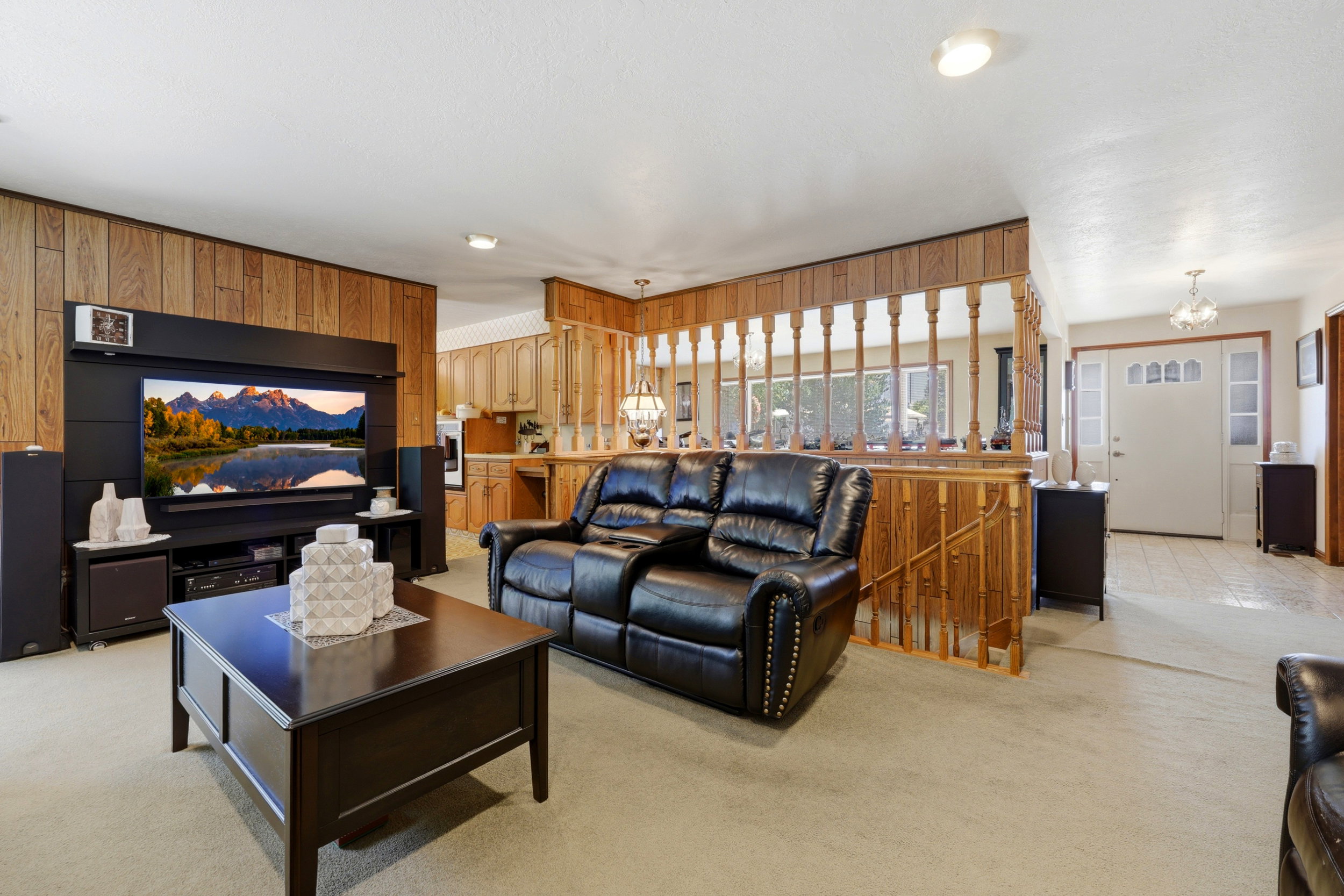 Spacious living area featuring wood-panel accent walls and light-toned carpeting