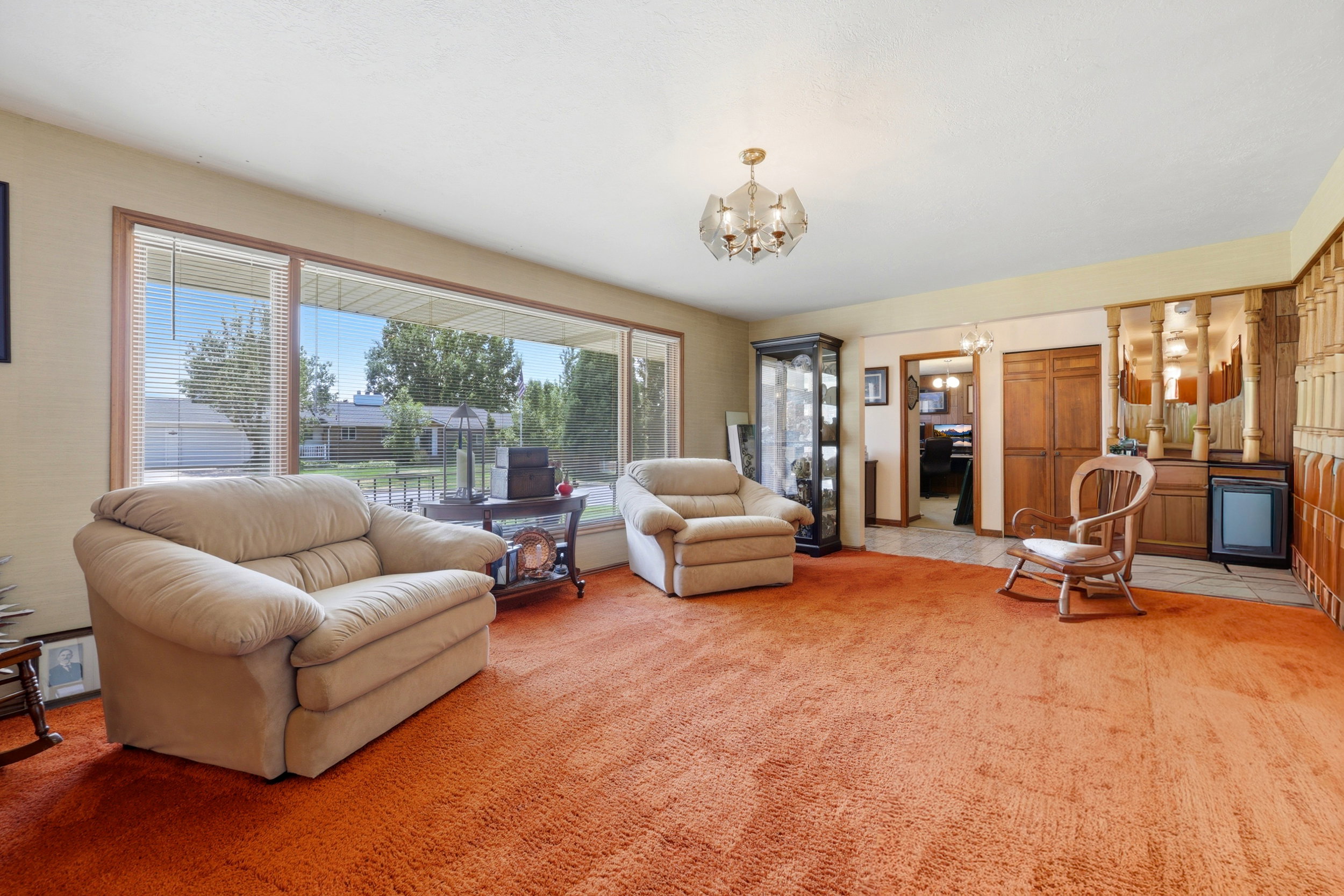 Living area featuring a large picture window, a built-in wet bar with wood paneling, and a contemporary chandelier
