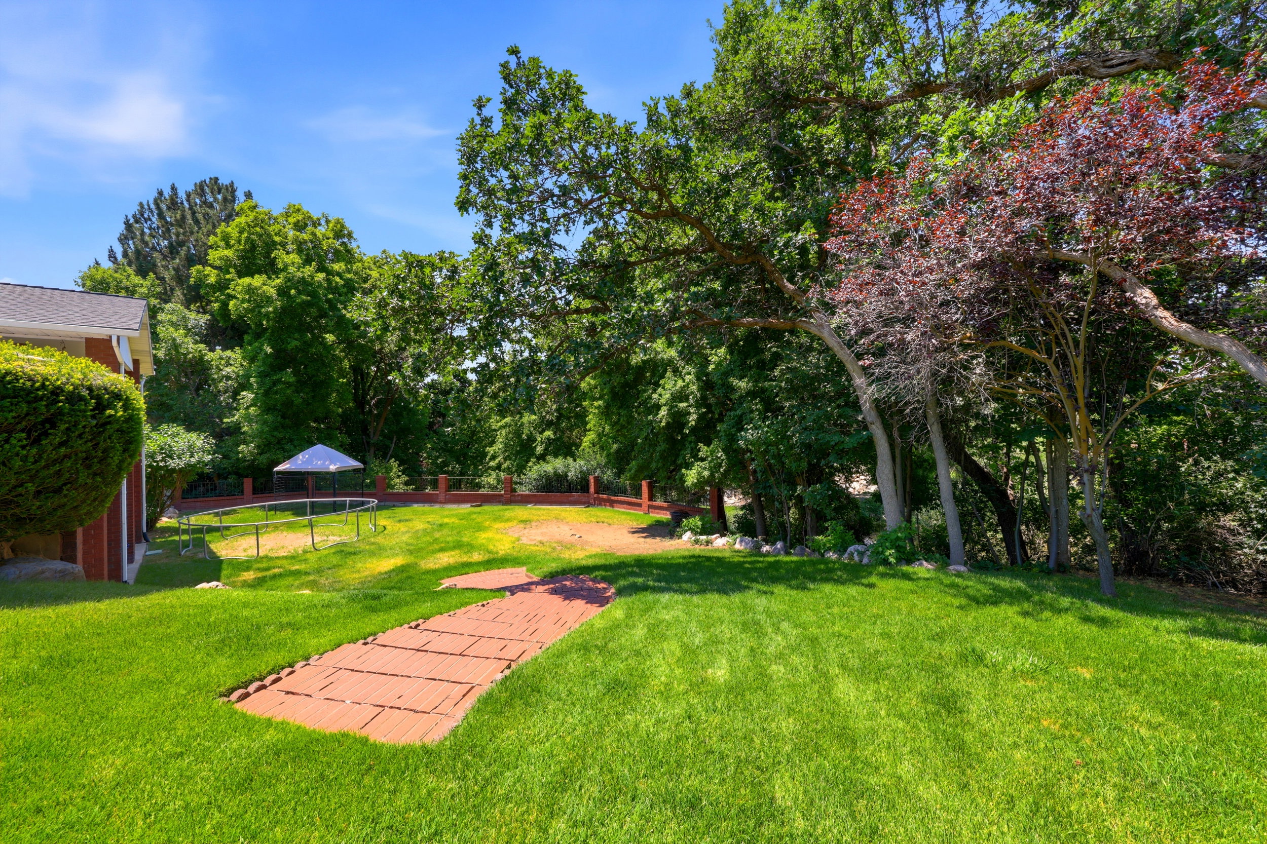 Expansive green lawn with mature trees and a paver pathway