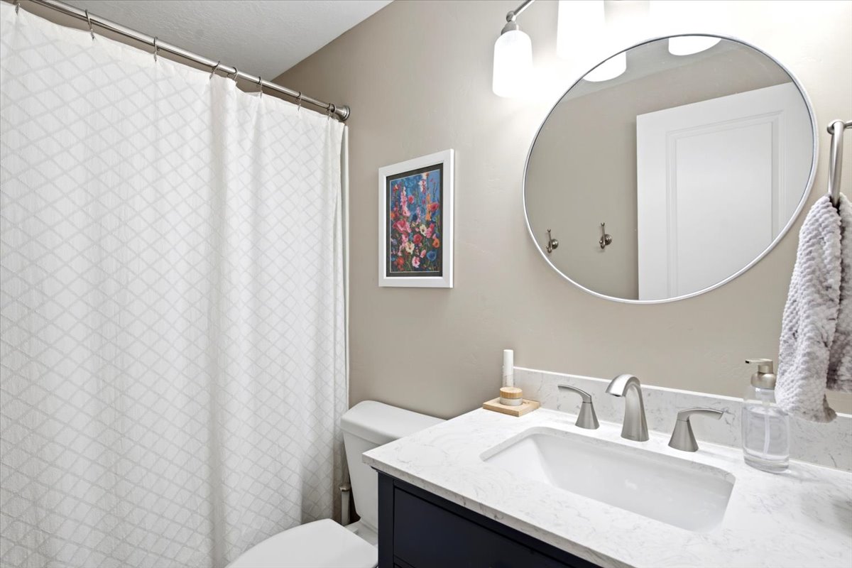 Modern bathroom vanity featuring a white rectangular undermount sink, a stone-finish countertop, and brushed nickel hardware