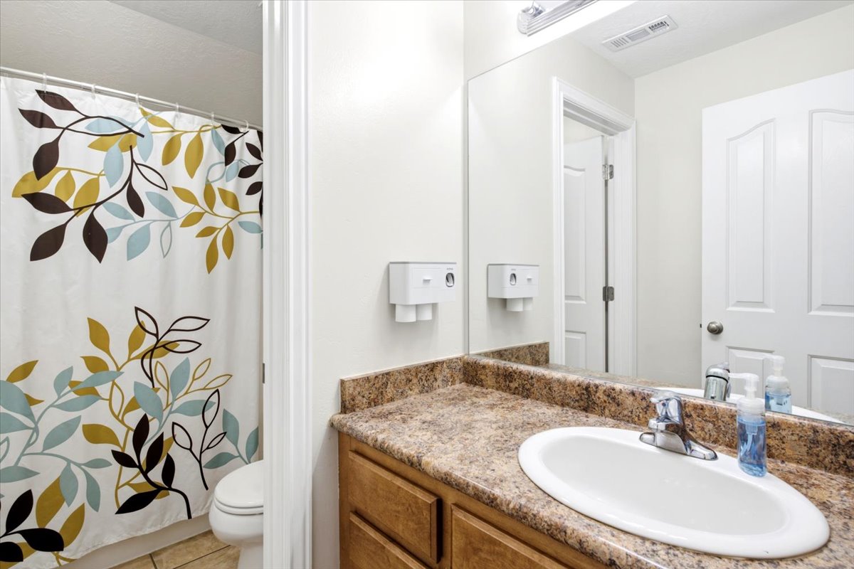 Bathroom vanity featuring a polished chrome faucet, an oval undermount sink, and a speckled countertop