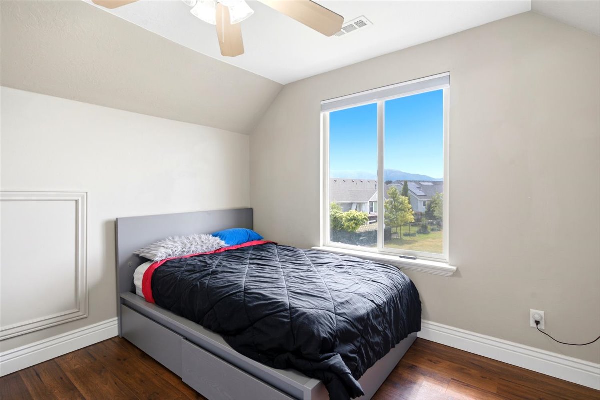 Bedroom featuring wood-finish flooring, a ceiling fan, and a large window