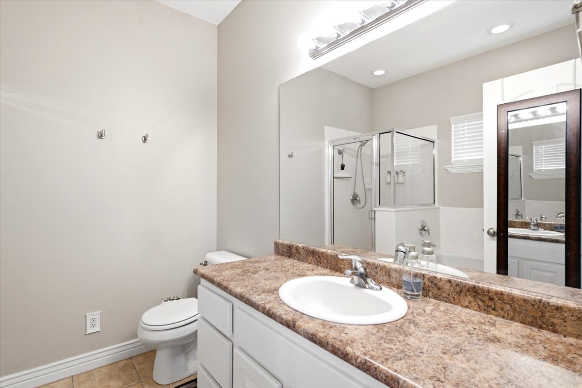 Bathroom with a spacious vanity featuring a stone-look countertop, an integrated sink, and an expansive mirror