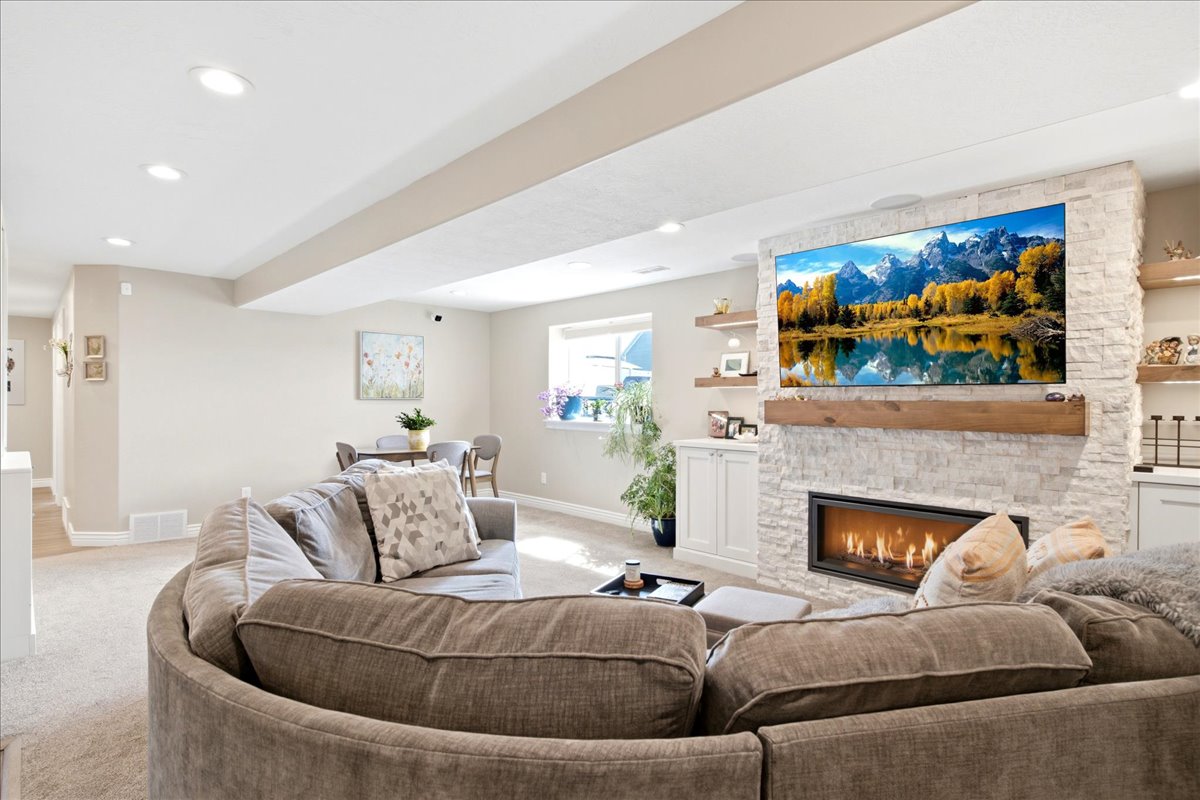 Living area featuring a stone accent wall, linear fireplace, recessed lighting, and carpeted flooring