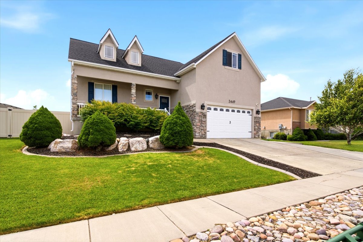 Two-story residence featuring a stucco and stone veneer exterior, an attached two-car garage, and a covered porch entry