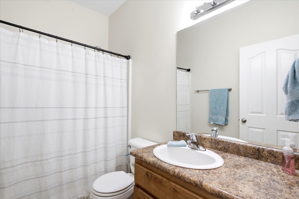 Bathroom featuring a vanity with a speckled countertop, an oval undermount sink, and a chrome faucet