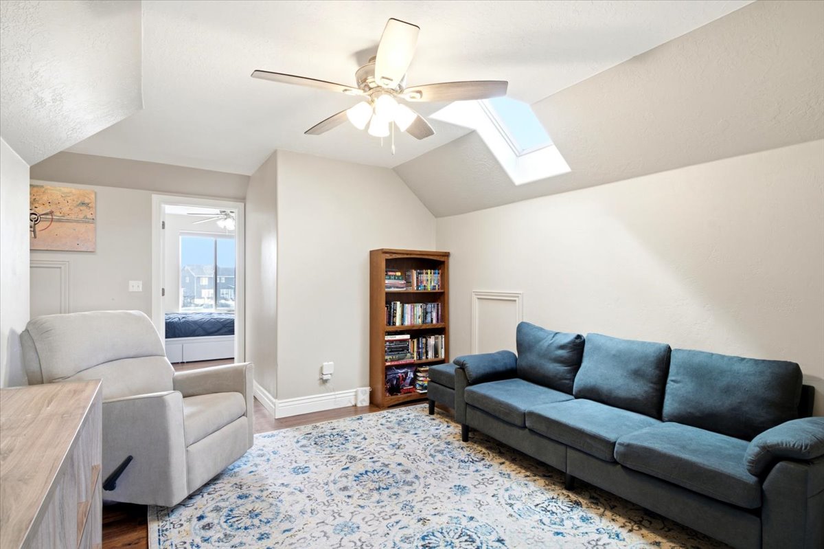 Room featuring sloped ceilings, a skylight, and wood-finish flooring