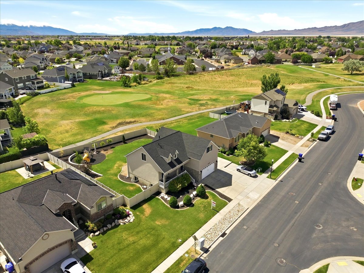Residential neighborhood featuring a paved street, established lawns, and a manicured golf course