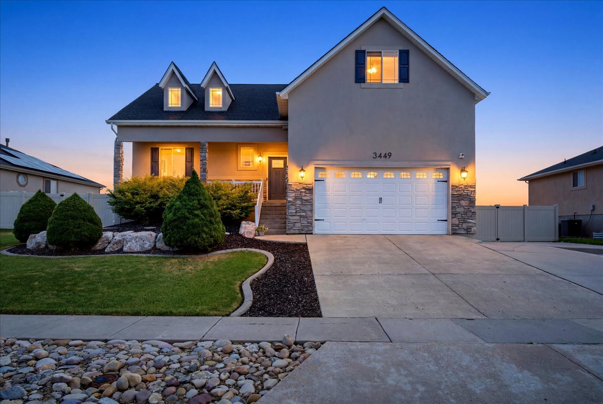 Stucco exterior featuring stone accents, a covered porch, an attached two-car garage, and a concrete driveway