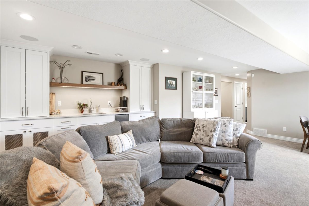 Entertainment area featuring a wet bar with white cabinetry, a built-in beverage refrigerator, and a wood-finish floating shelf