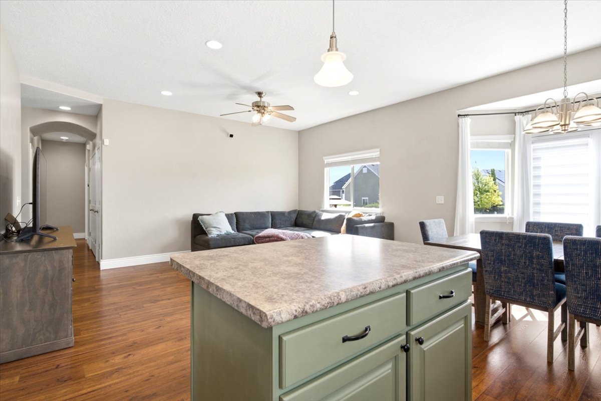 Kitchen island with green cabinetry and stone-finish countertop