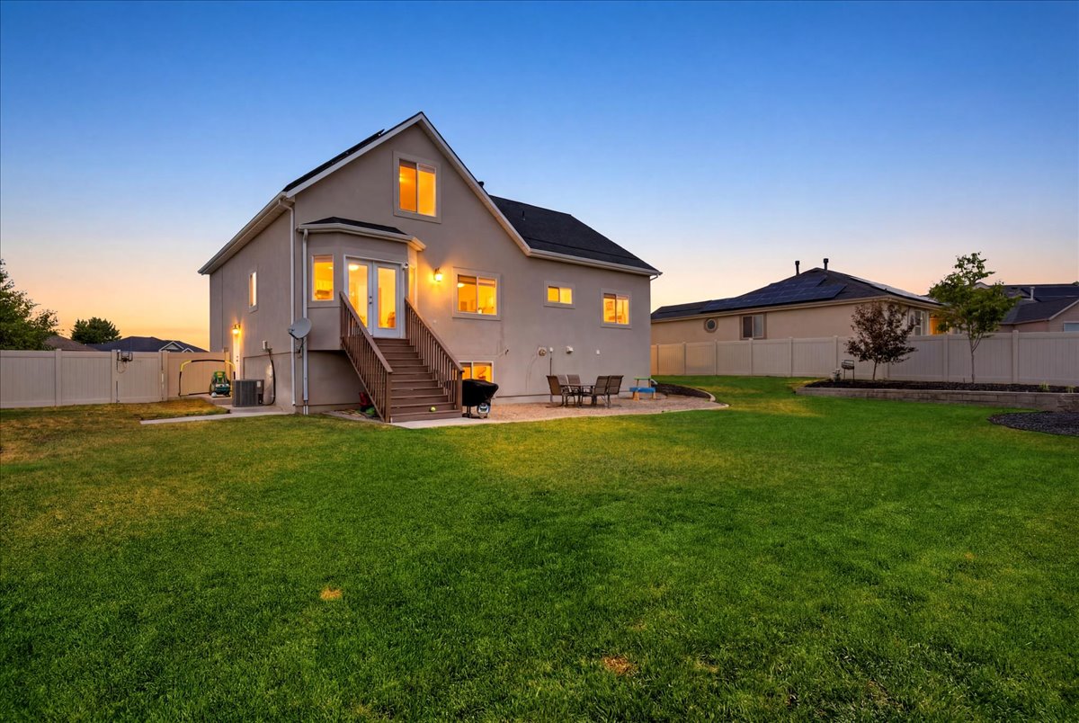 Expansive backyard featuring a lush lawn, a patio with pavers, and a raised garden bed