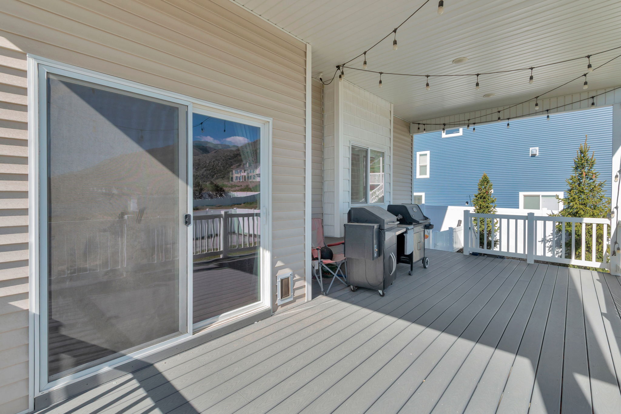 Spacious covered deck featuring composite decking, white railing, and string lighting
