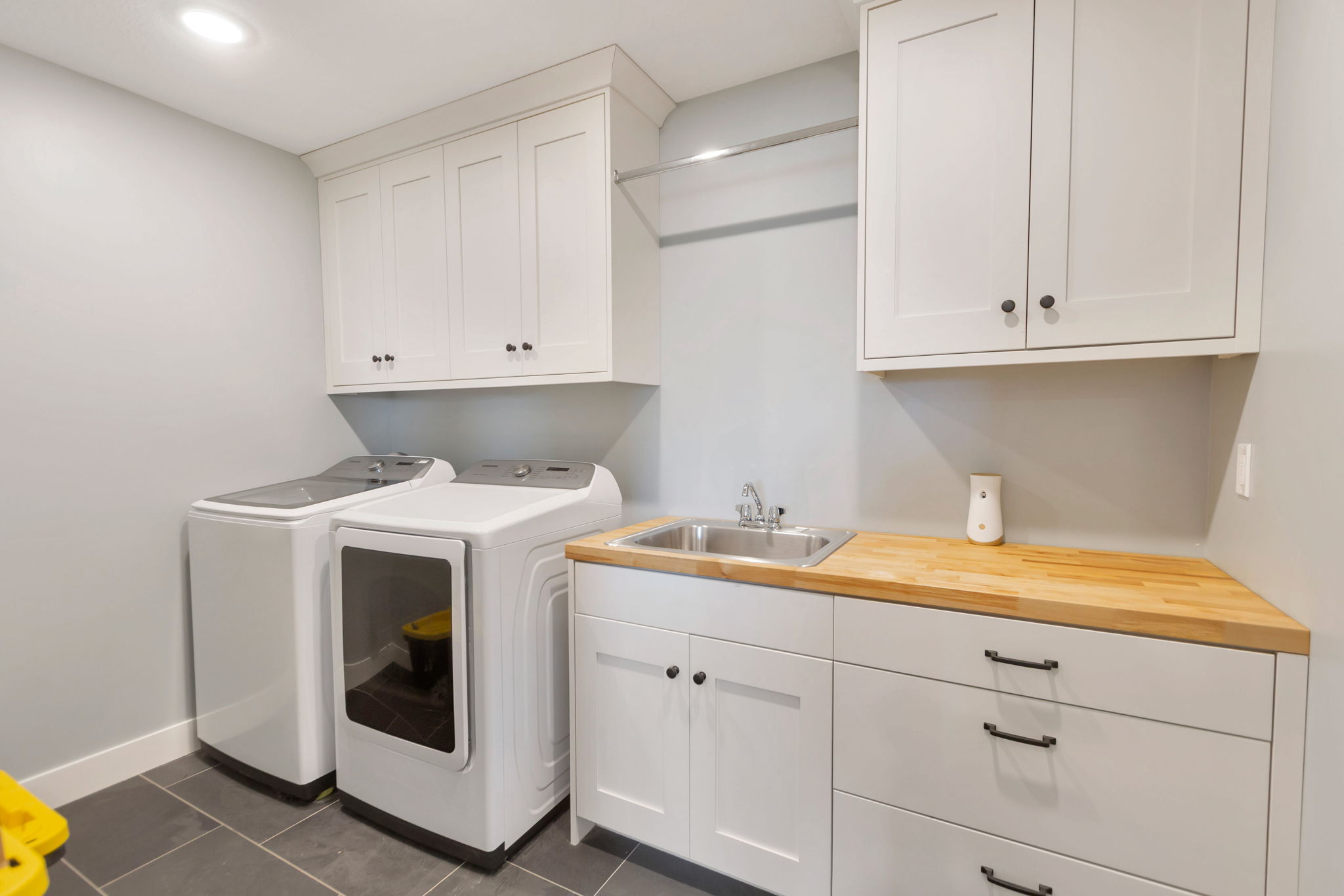 Dedicated laundry room with tile flooring, shaker-style cabinetry, and wood-finish countertops
