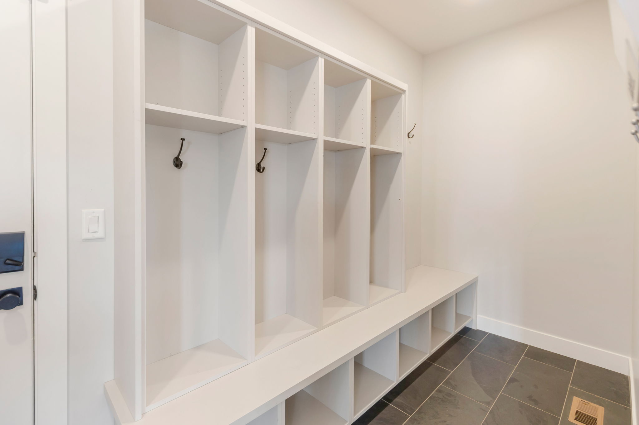 Built-in mudroom storage featuring individual cubbies with hooks, a bench seat, and lower storage compartments