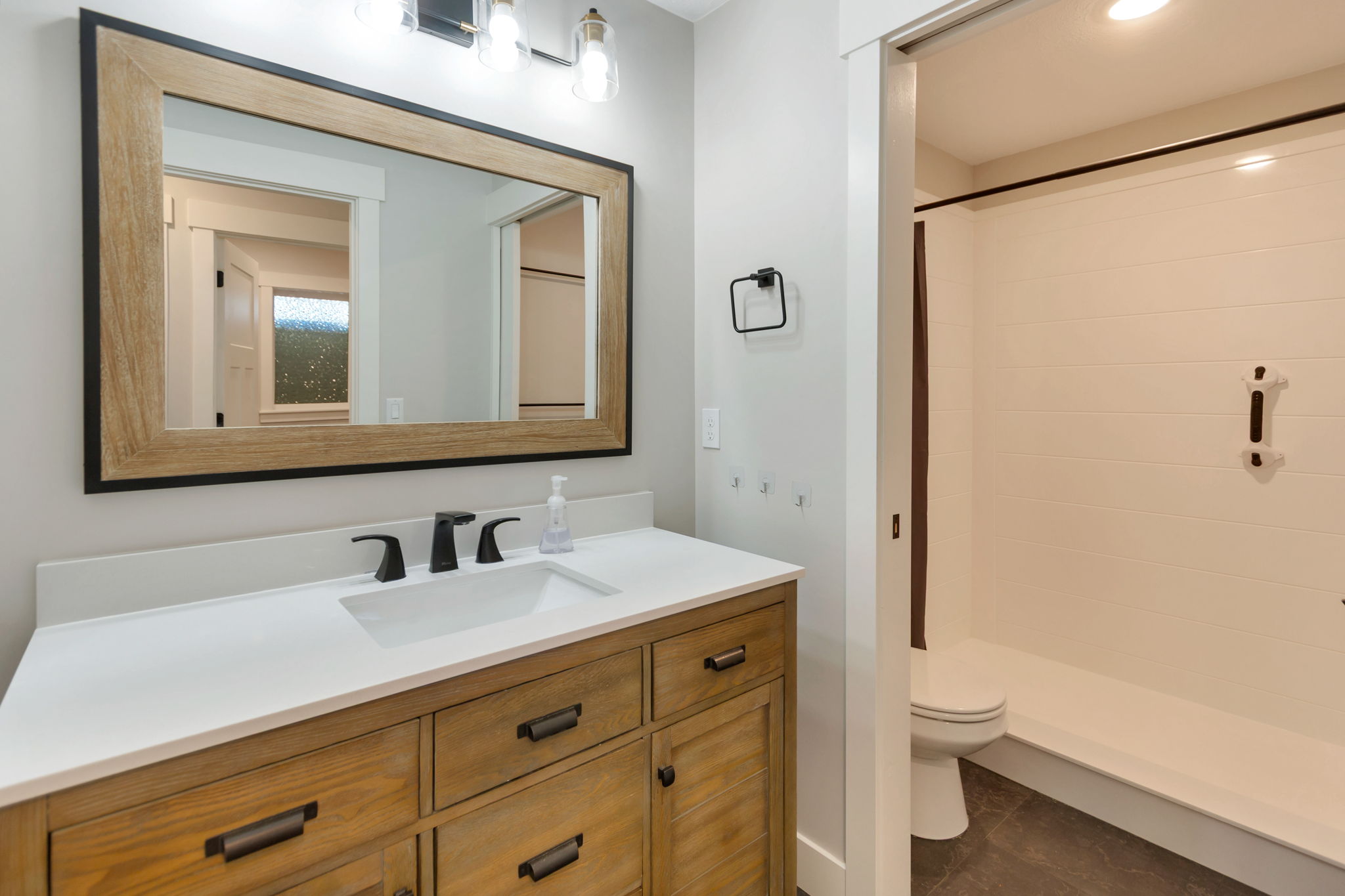 Bathroom vanity featuring a wood-finish cabinet, white countertop, and dark-toned hardware