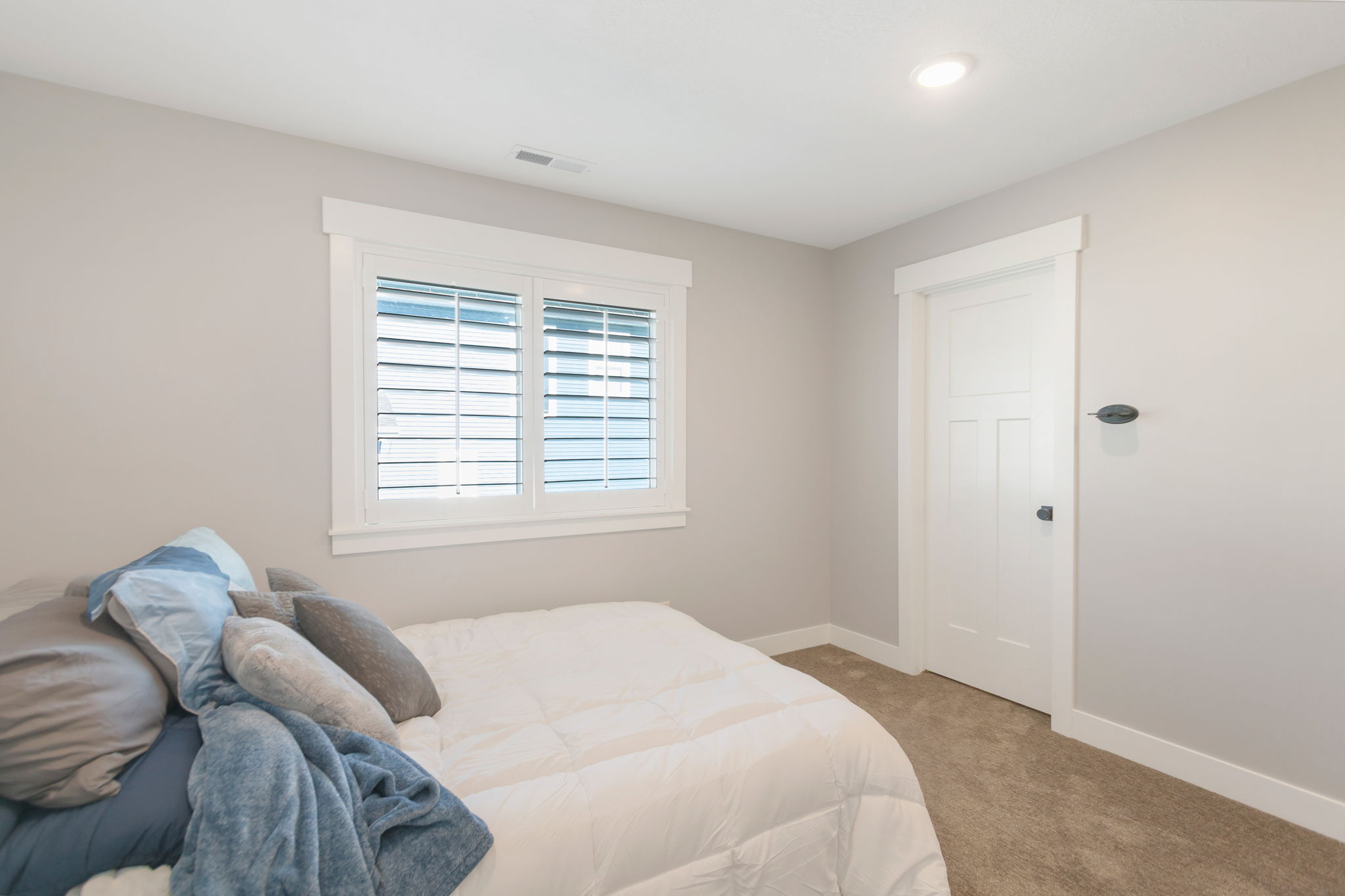 Bedroom featuring a double window with plantation shutters, recessed ceiling lighting, and neutral wall paint