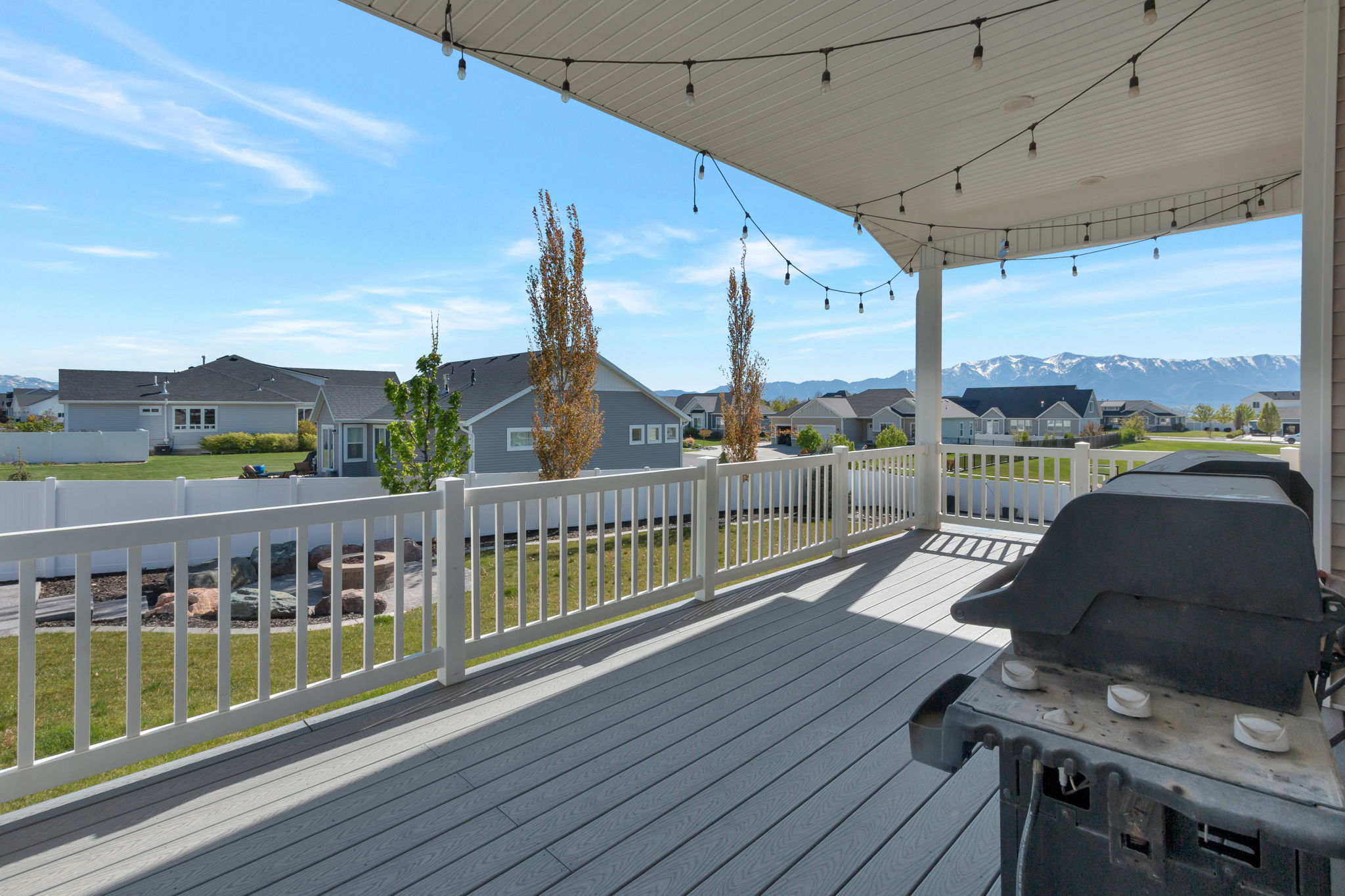 Covered back deck featuring composite decking and string lighting