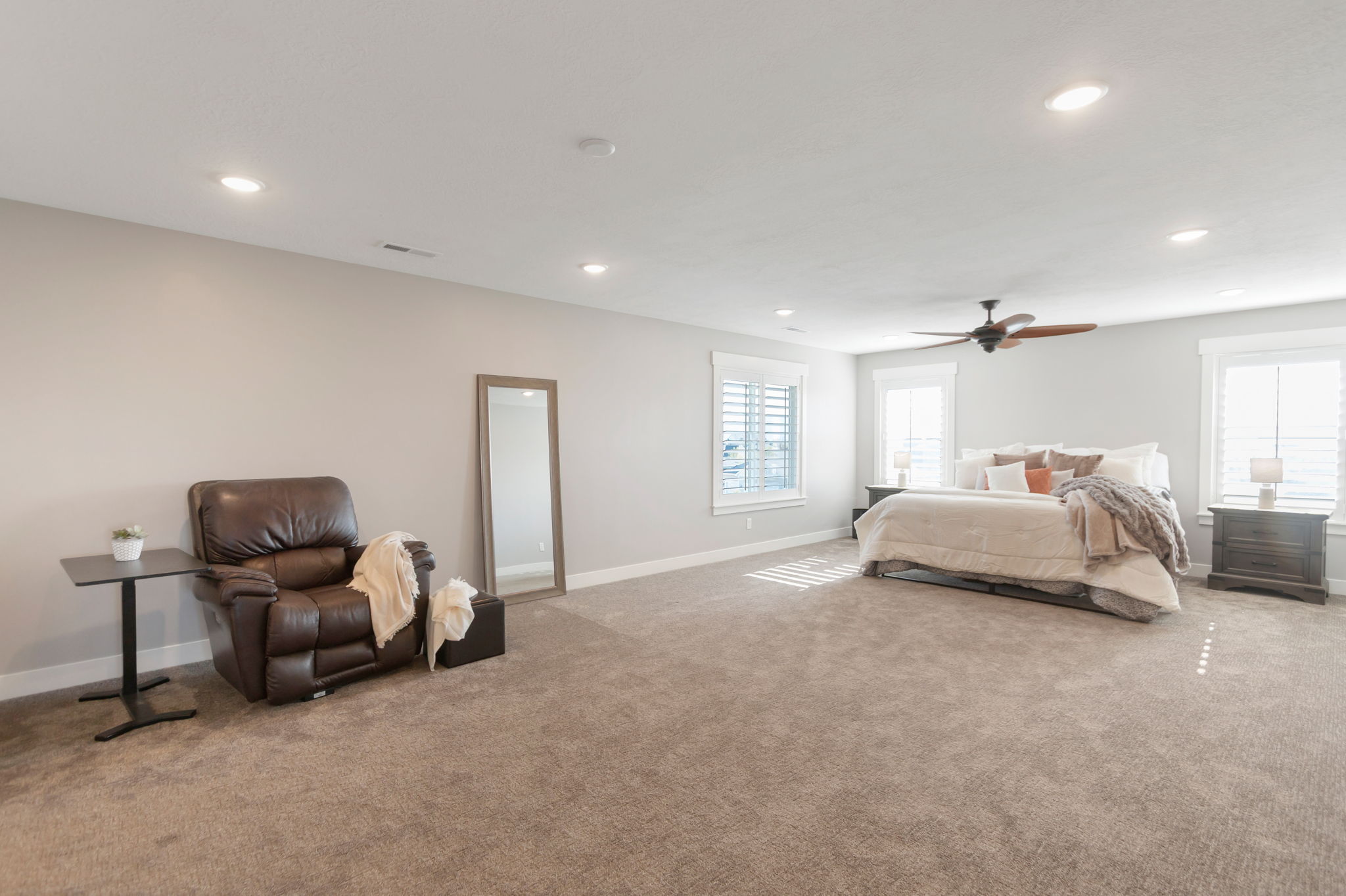 Spacious carpeted room featuring multiple windows with plantation shutters, recessed lighting, and a ceiling fan