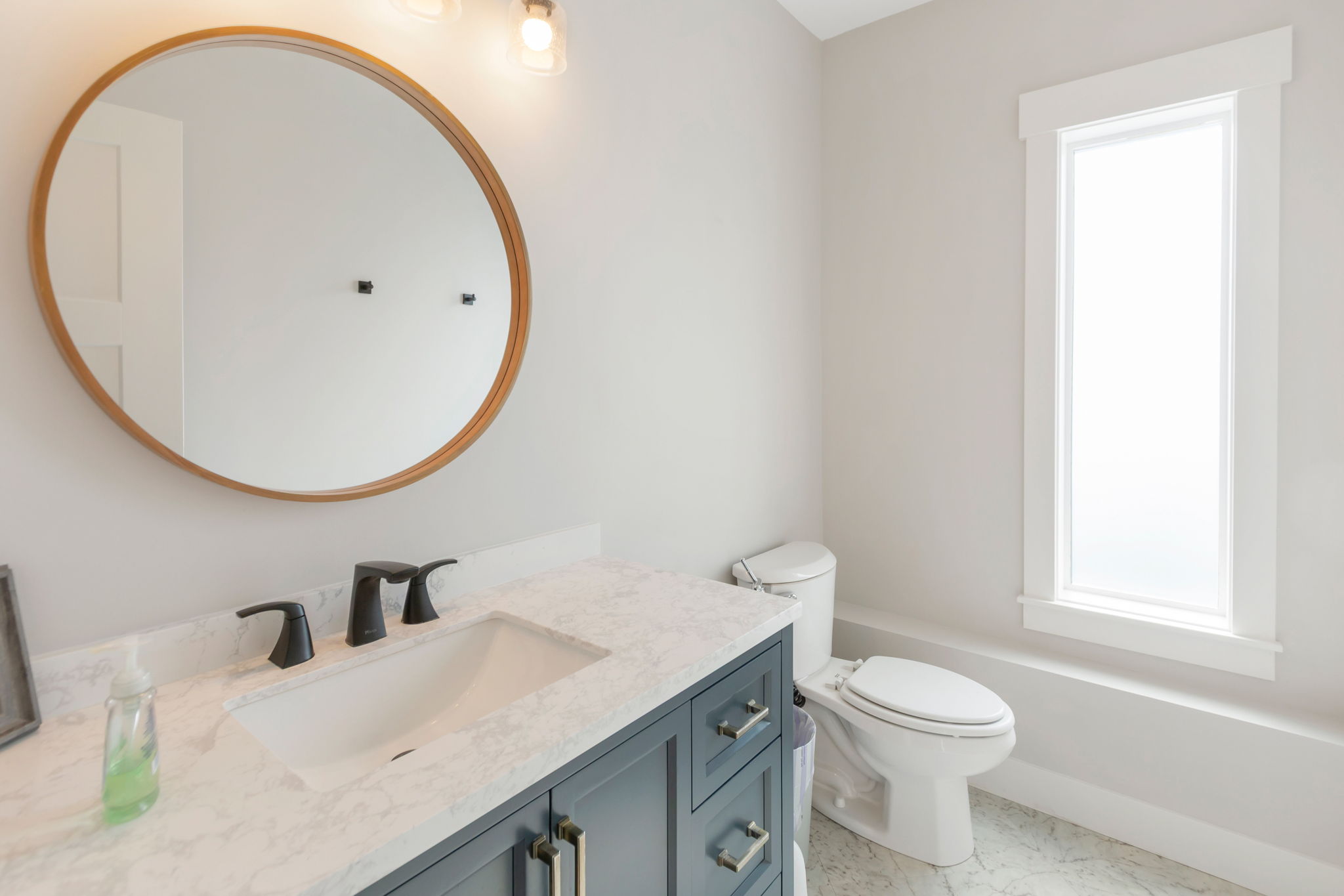 Bathroom vanity featuring a vessel sink, stone-finish countertop, and dark cabinetry with brass hardware