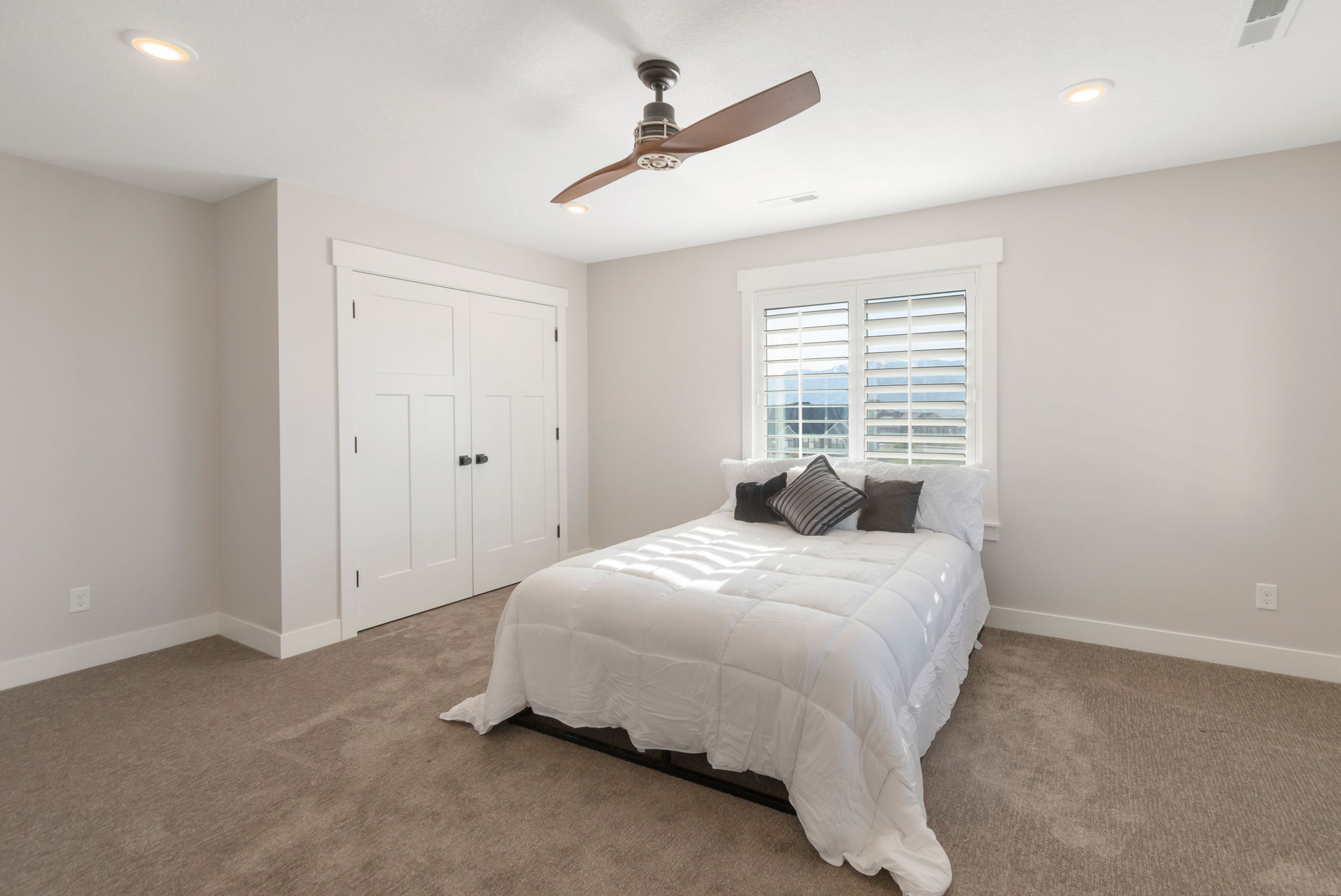 Carpeted bedroom featuring a double window with plantation shutters, recessed lighting, and a ceiling fan