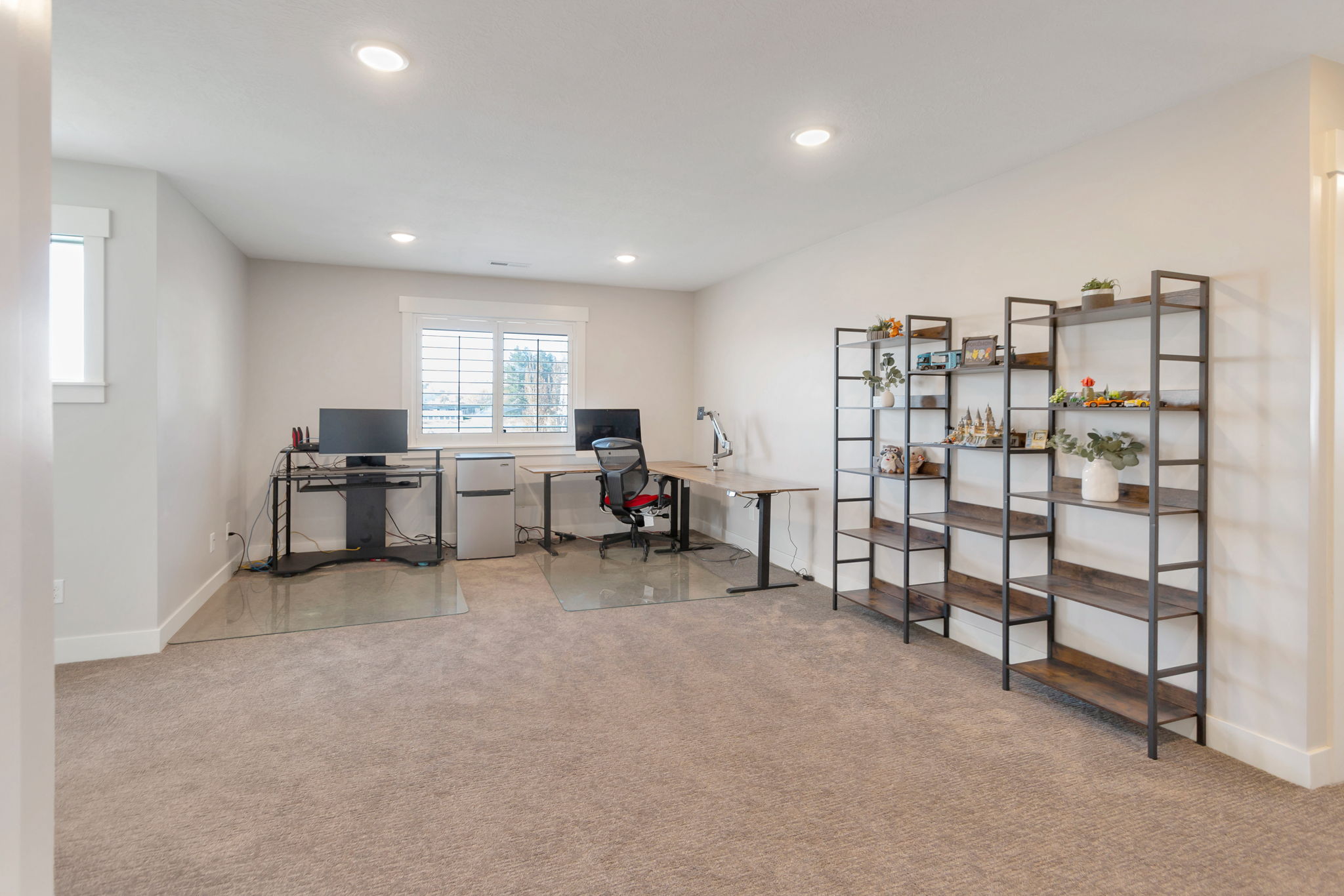 Expansive room featuring recessed lighting, a window with white louvered blinds, and neutral carpet flooring