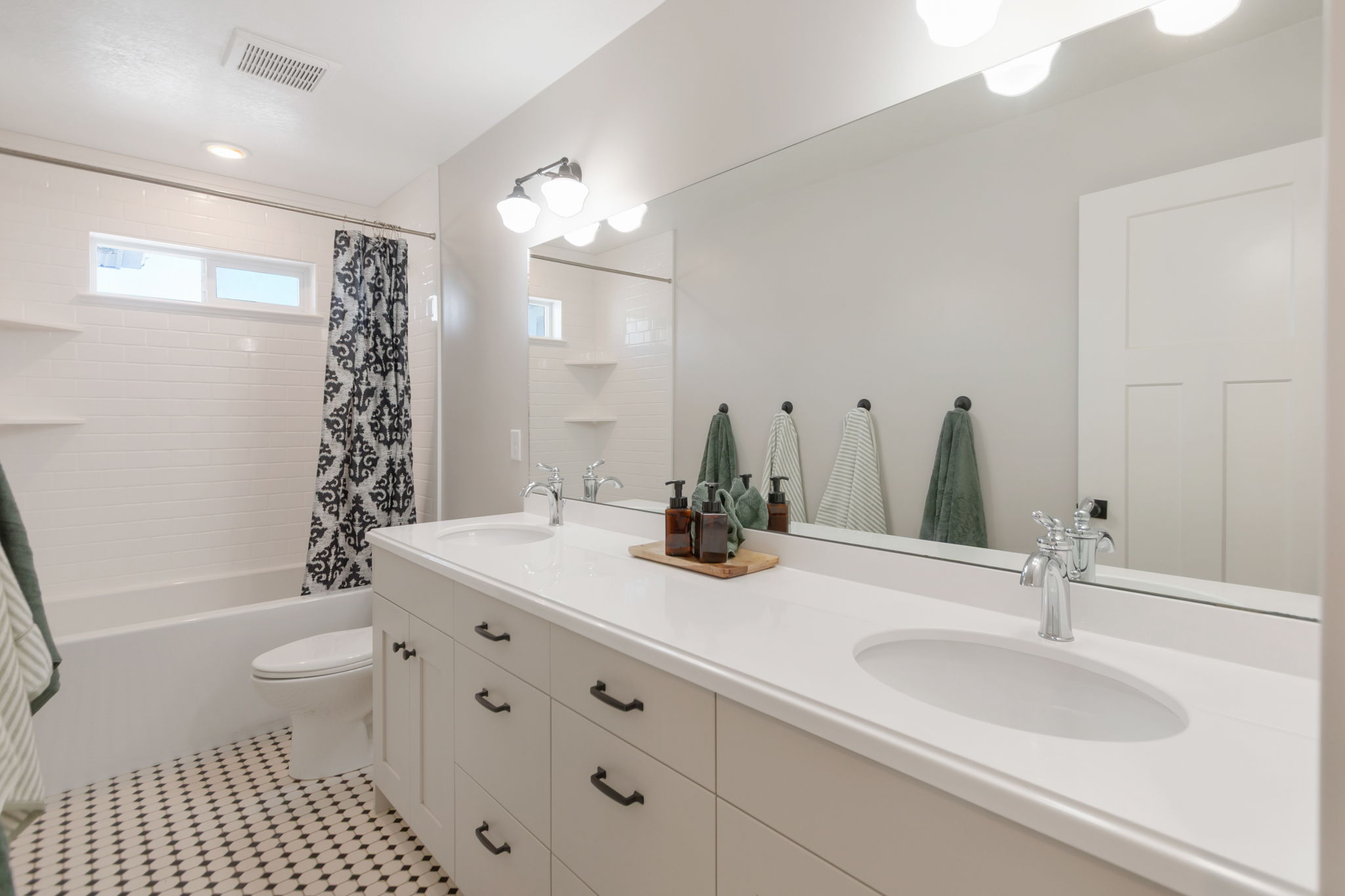 Bathroom featuring a dual-sink vanity with white cabinetry and a solid surface countertop