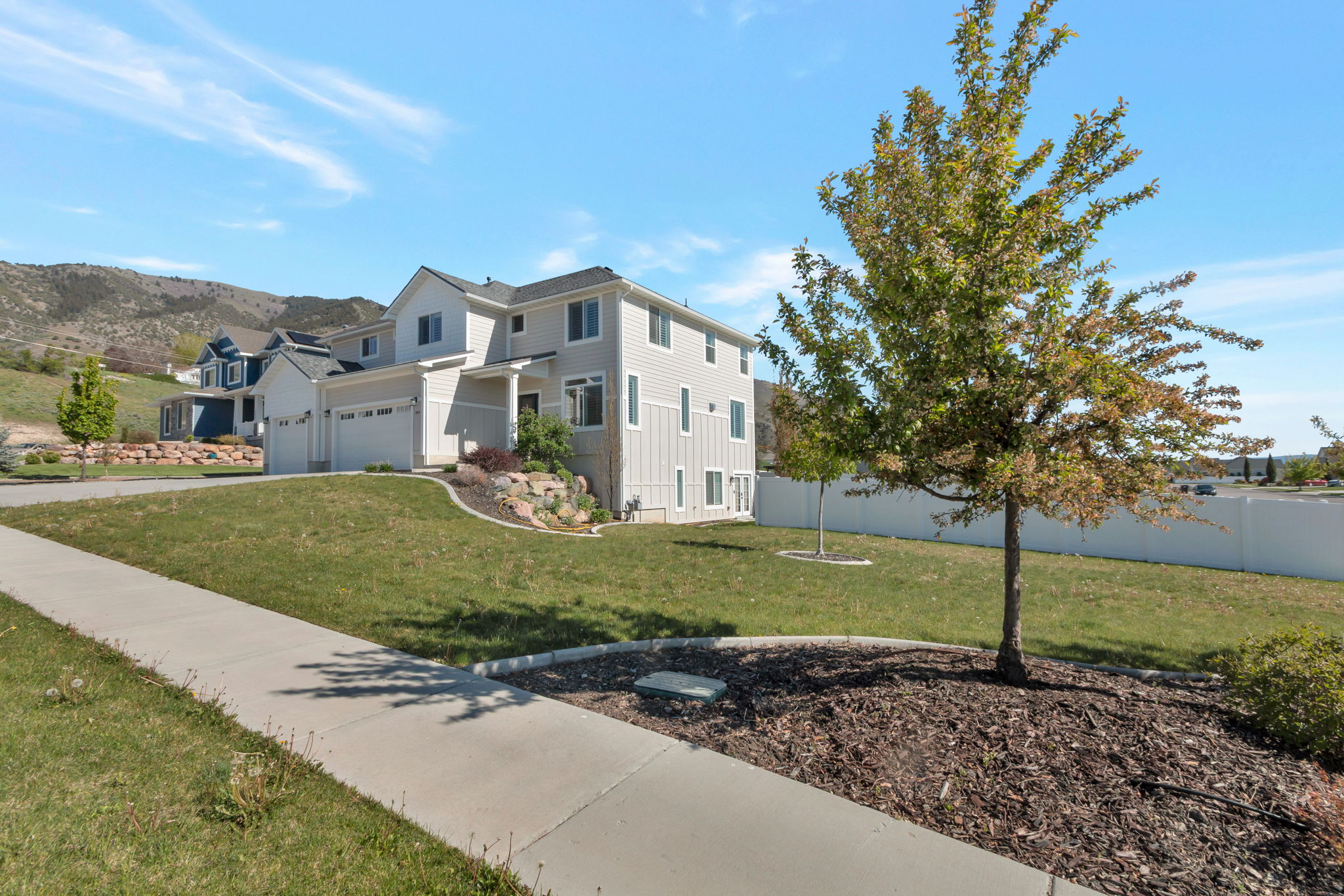Two-story residence featuring a light-toned exterior with white trim and multiple windows