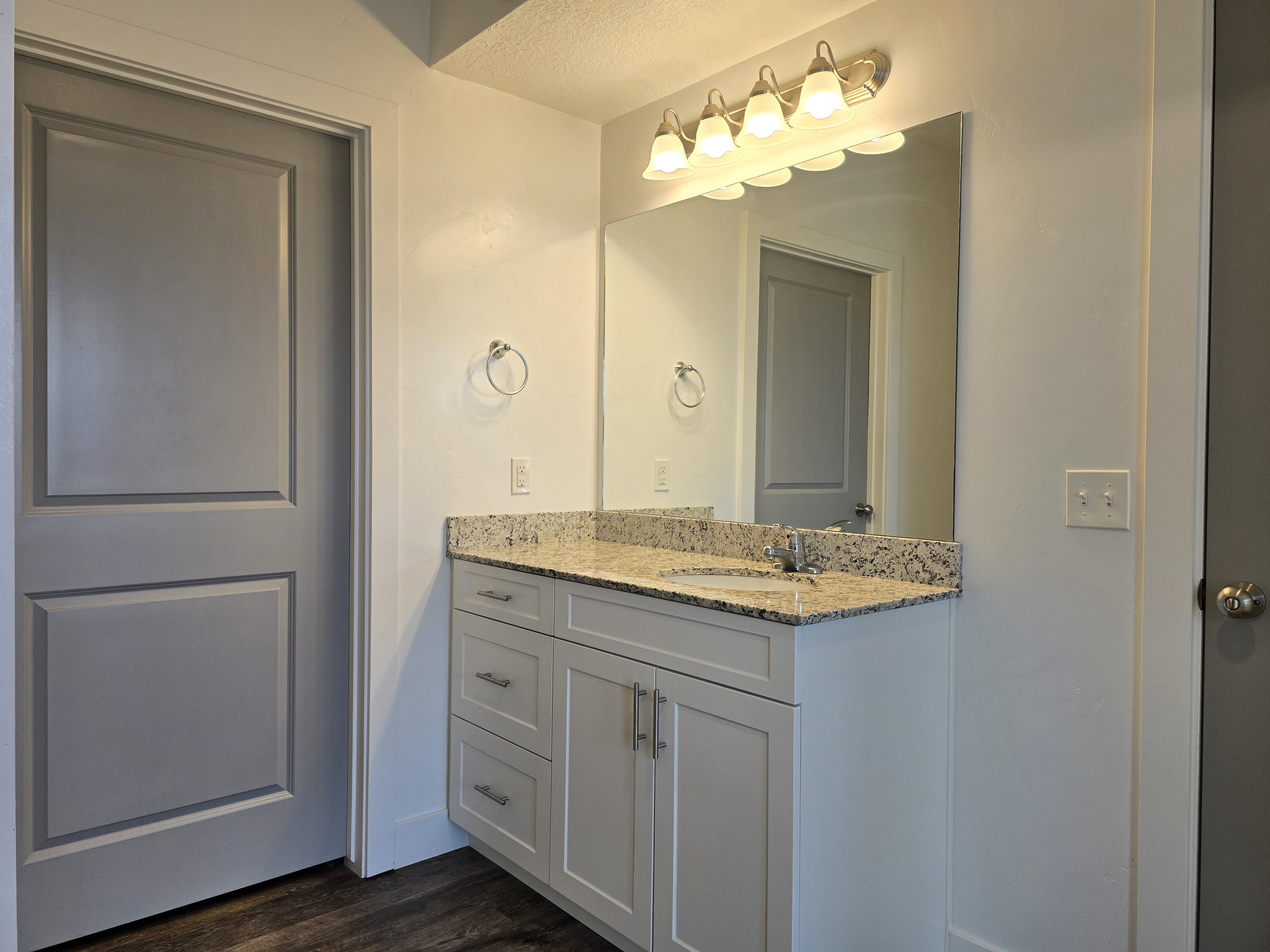 Bathroom vanity featuring a light granite countertop, undermount sink, and brushed nickel hardware