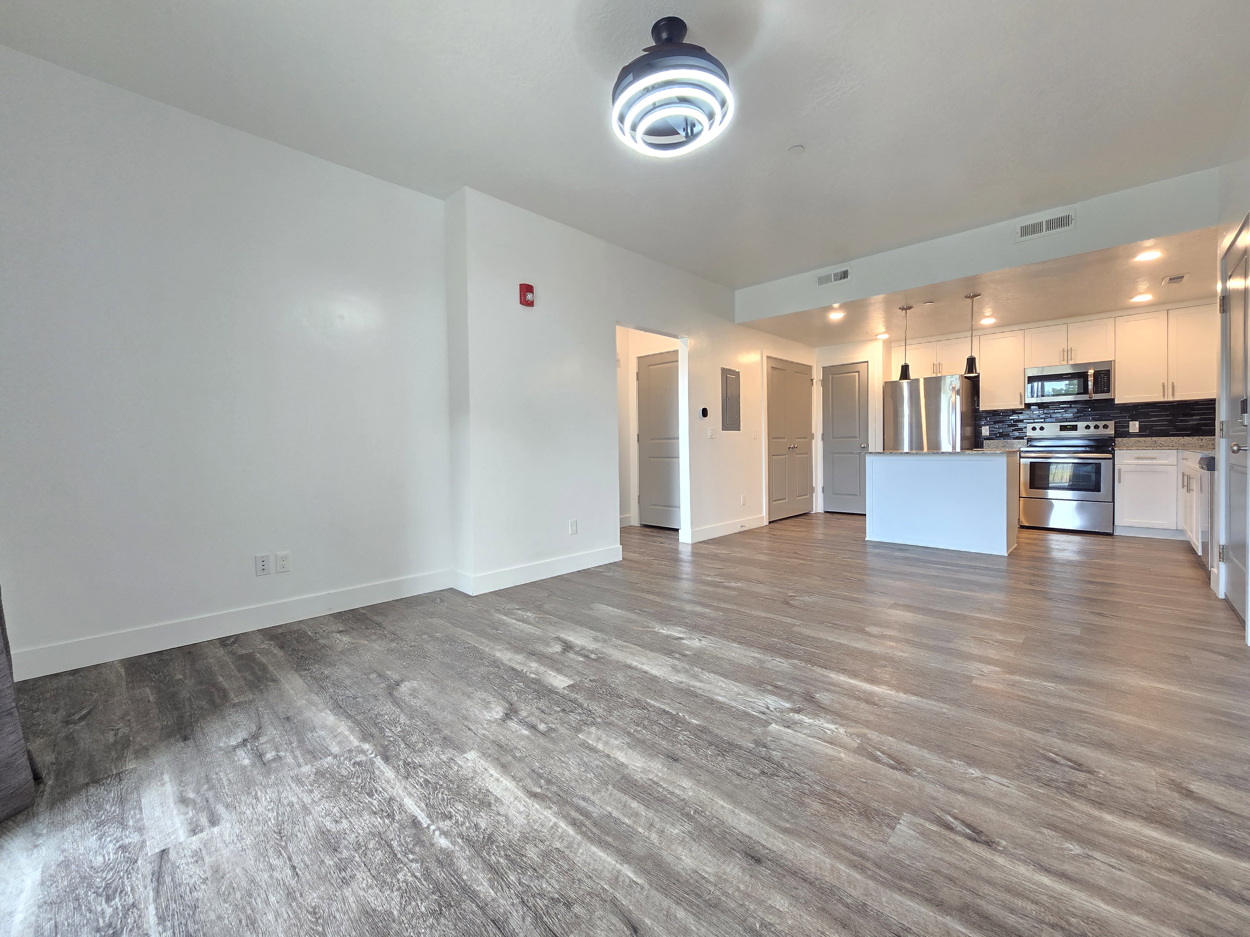 Open-concept living space featuring wood-finish flooring, white walls, and a contemporary ceiling fixture