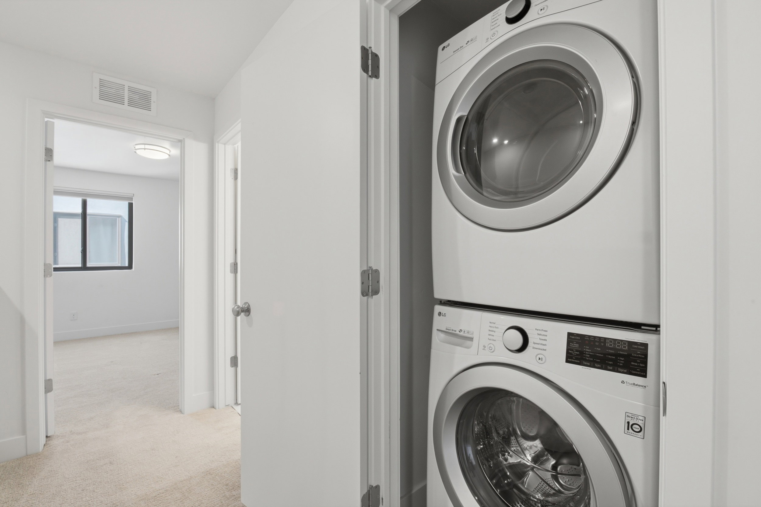 Dedicated laundry closet featuring a stacked washer and dryer - which are included in the purchase!